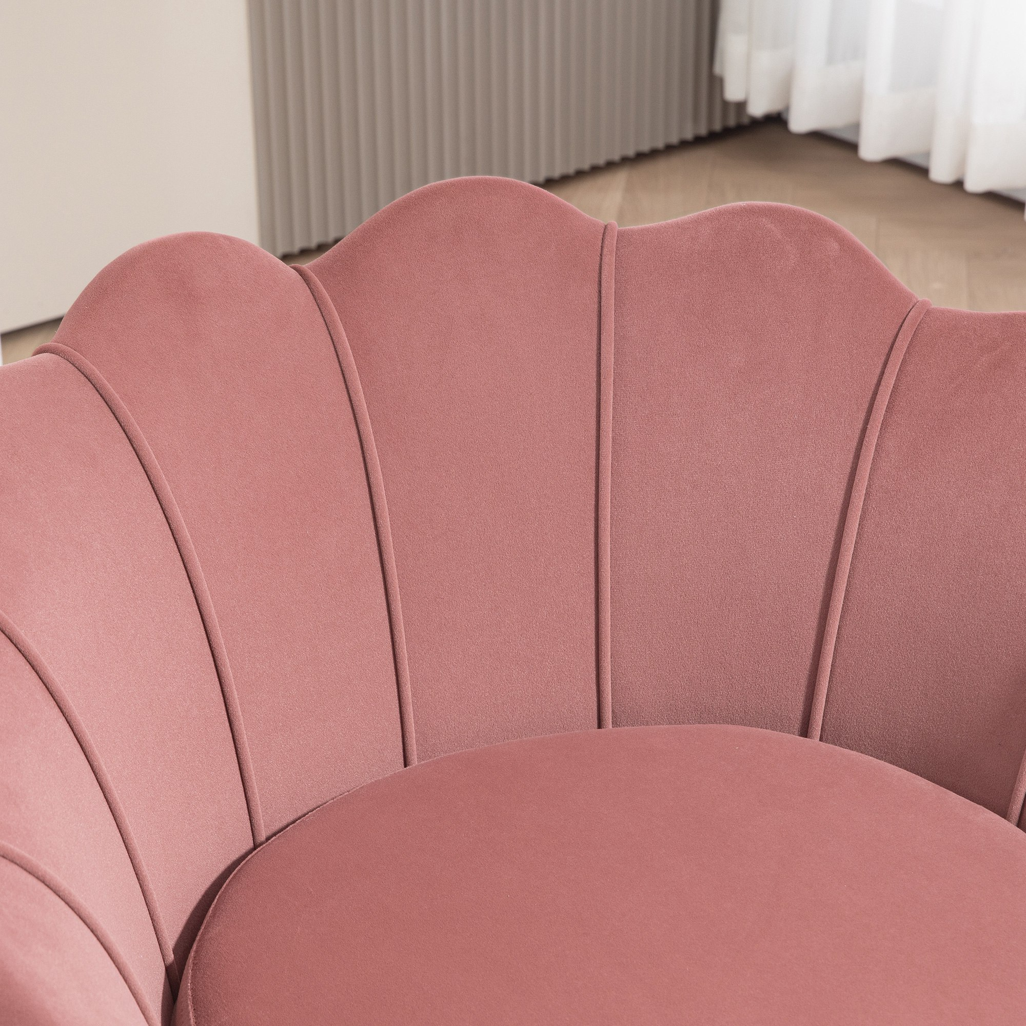 Un sillón rosa con respaldo festoneado y asiento redondo.