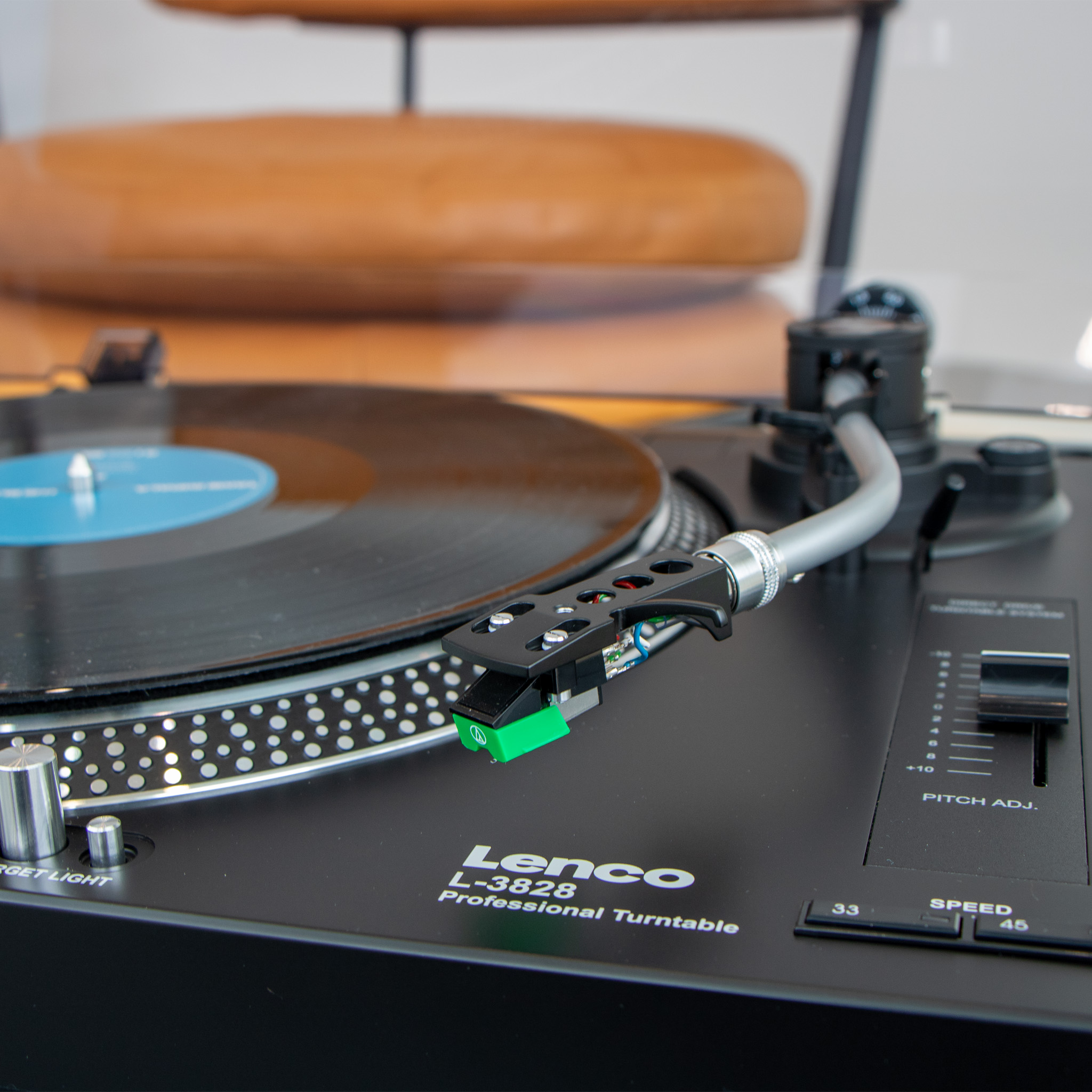 Een Lenco L-3828 platenspeler met toonarm en vinylplaat.