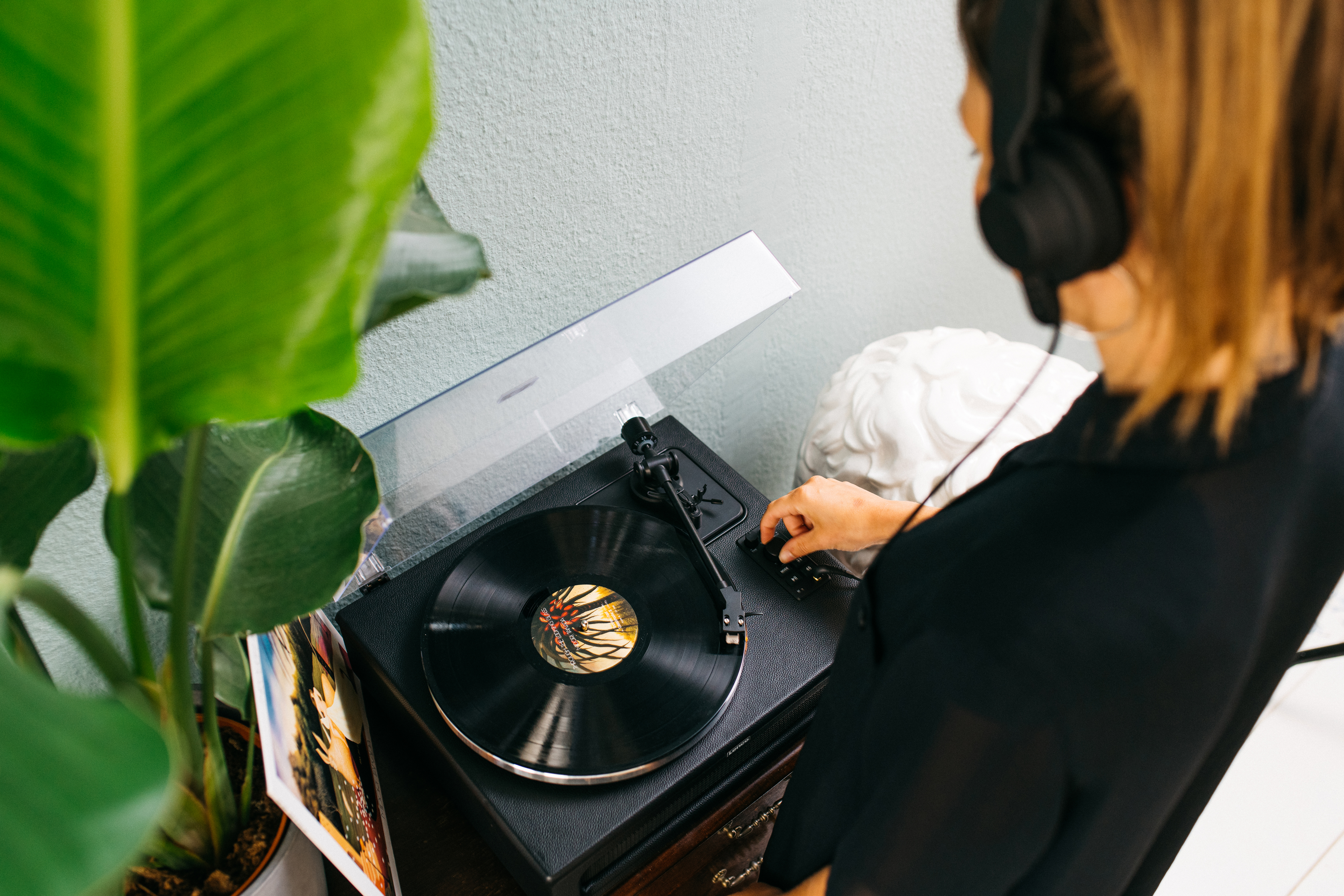 Una persona con auriculares ajusta un disco en un tocadiscos.