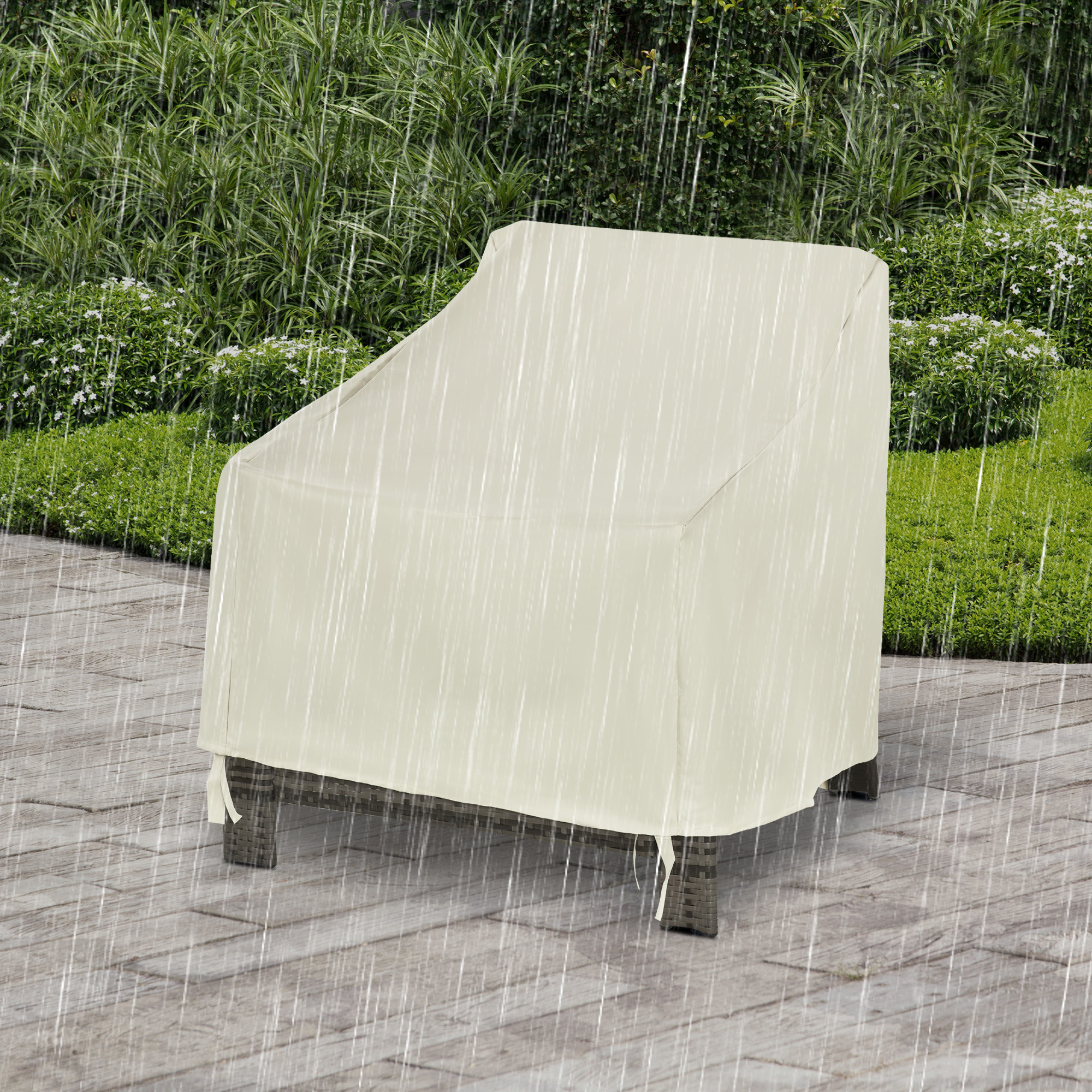 Una funda de silla clara protege una silla de mimbre bajo la lluvia en un patio de madera.