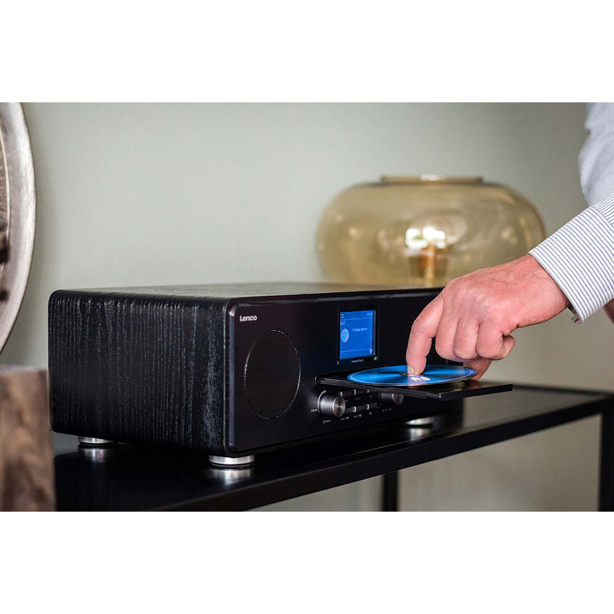 Mężczyzna wkłada płytę CD do czarnego radia Lenco z wyświetlaczem.