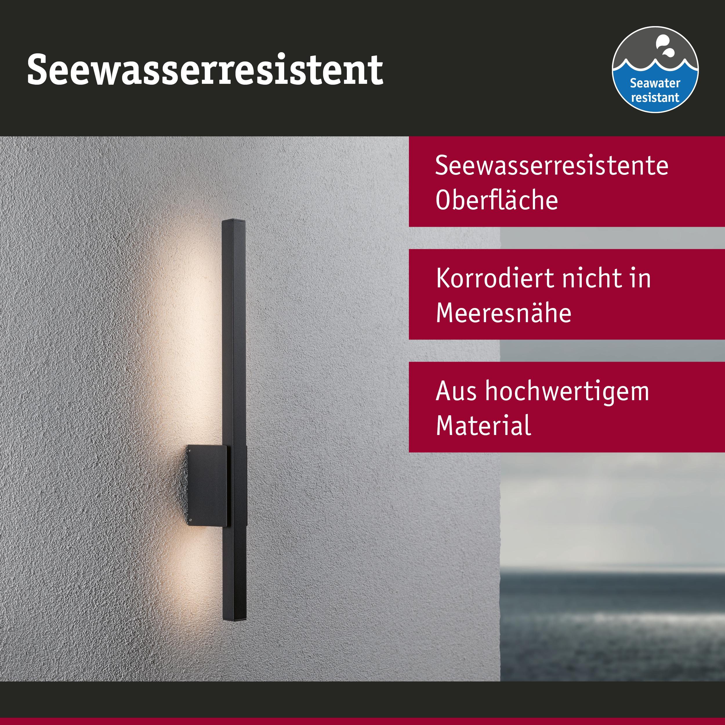 Eine schwarze Wandleuchte mit warmem Licht leuchtet auf einer strukturierten Wand.