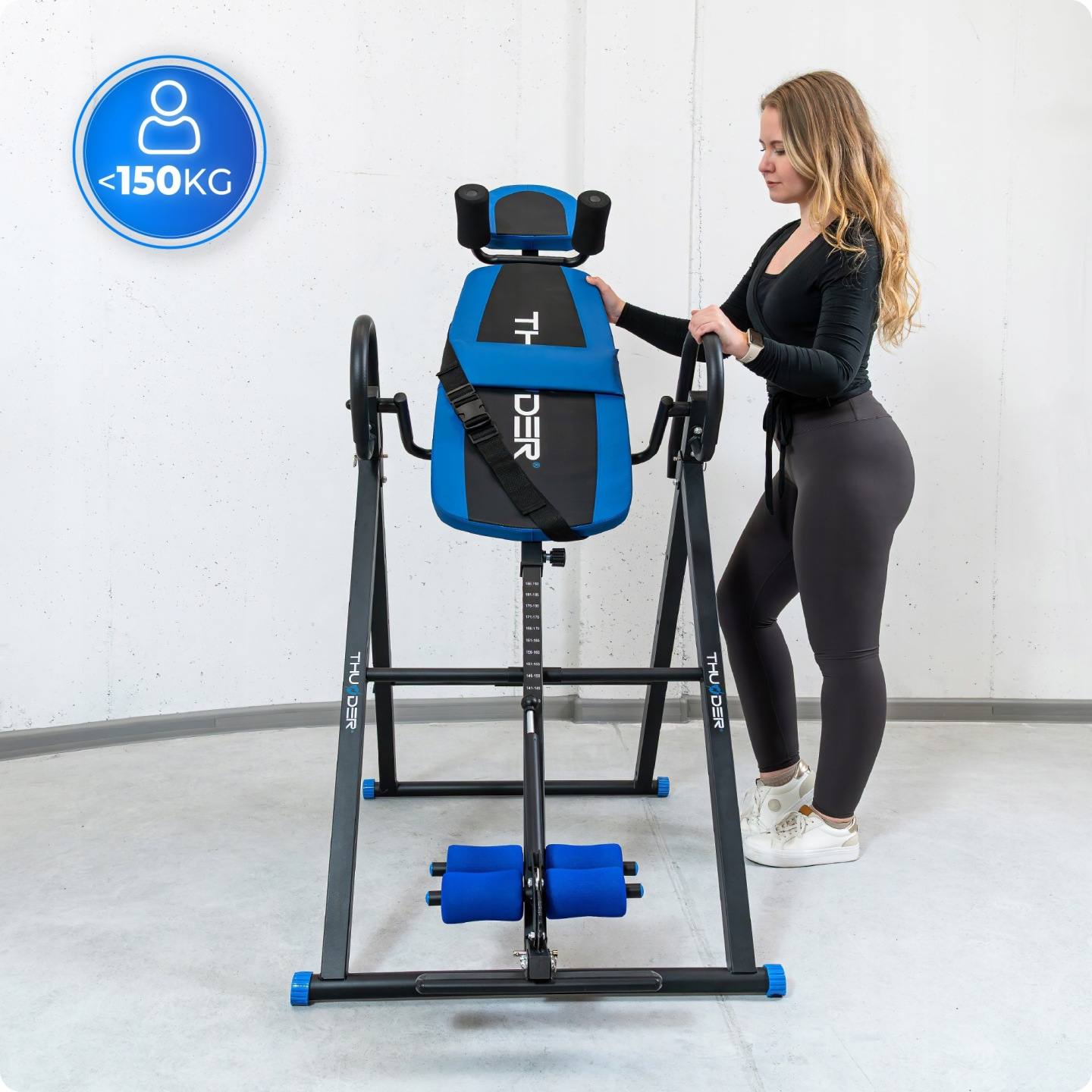 Kobieta w czerni stoi obok niebiesko-czarnej ławki inwersyjnej z limitem wagi <lt/>150KG.