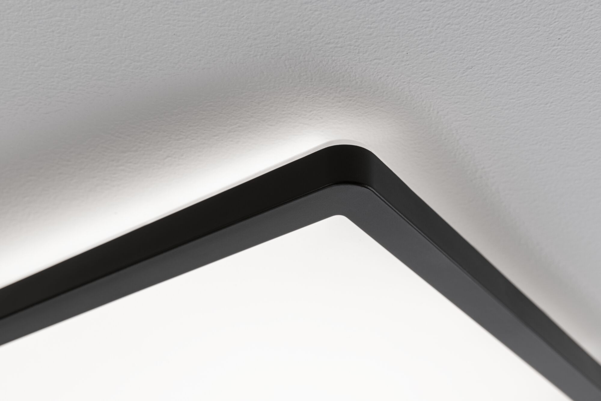 Una cornice rettangolare nera con una superficie illuminata bianca contro un soffitto bianco testurizzato.