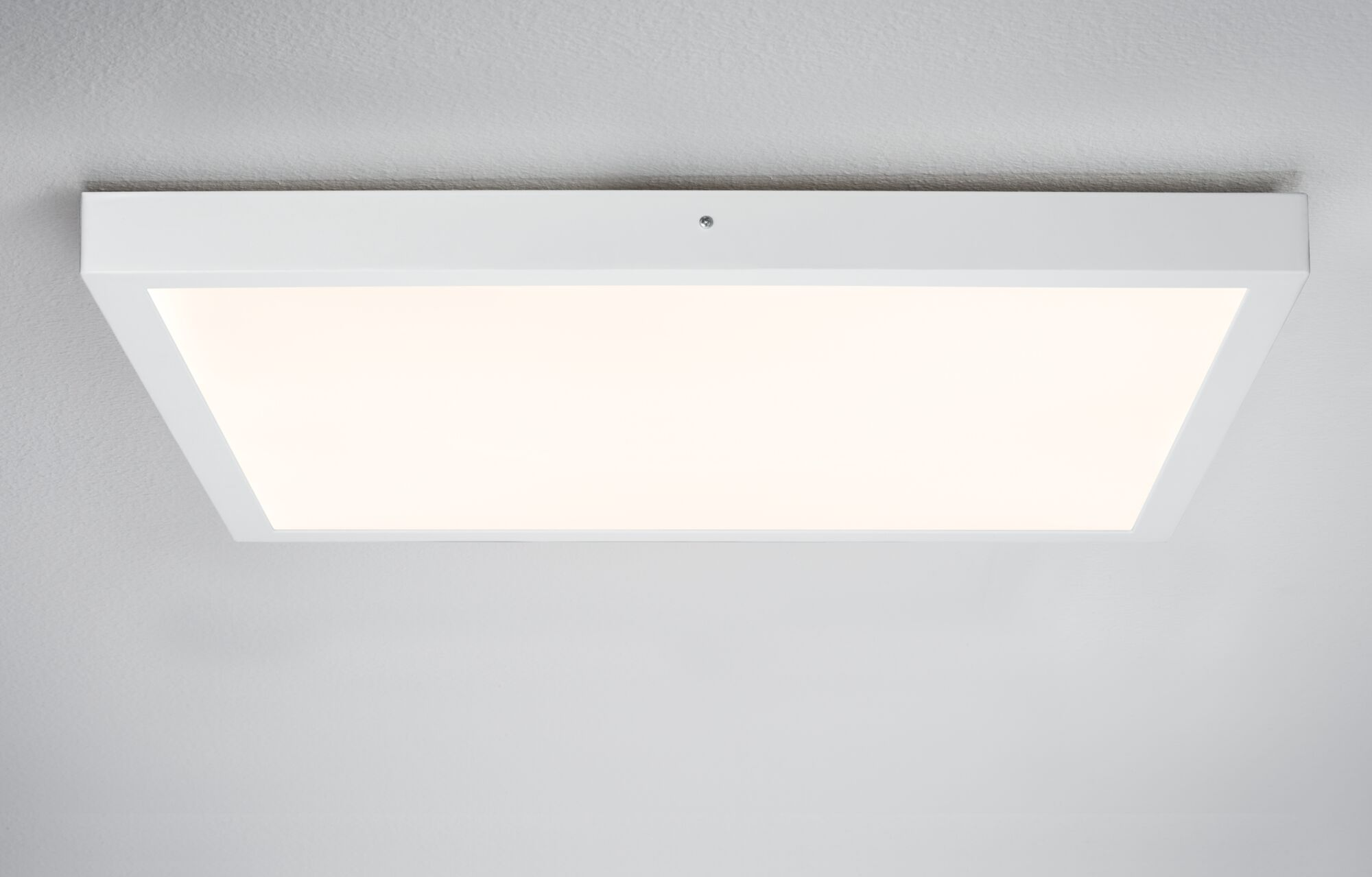 Eine weiße rechteckige Deckenleuchte mit einem hellen, diffusen Licht auf einer strukturierten Decke.