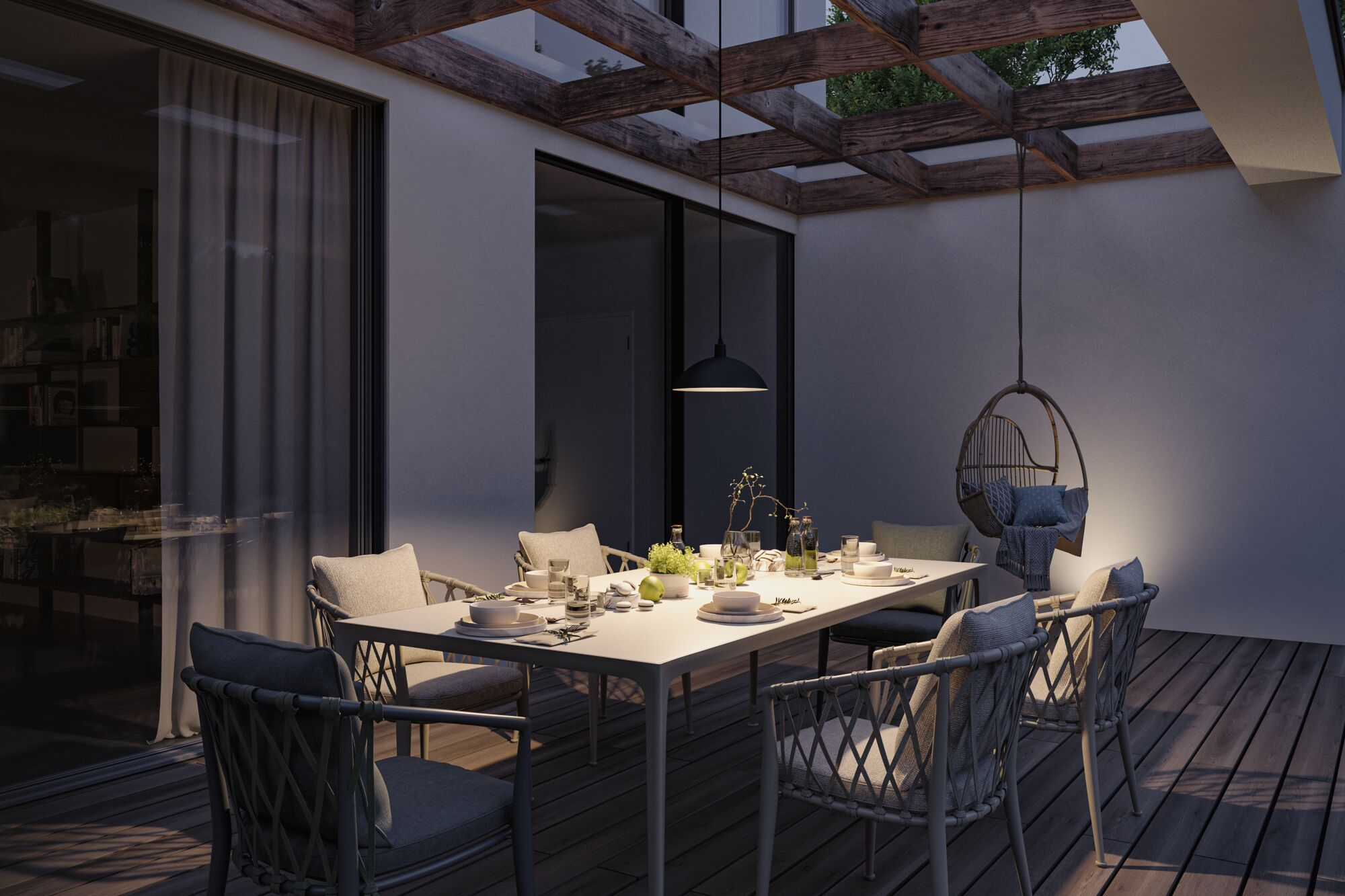 Ein beleuchteter Esstisch mit Stühlen unter einer Holzpergola bei Nacht.
