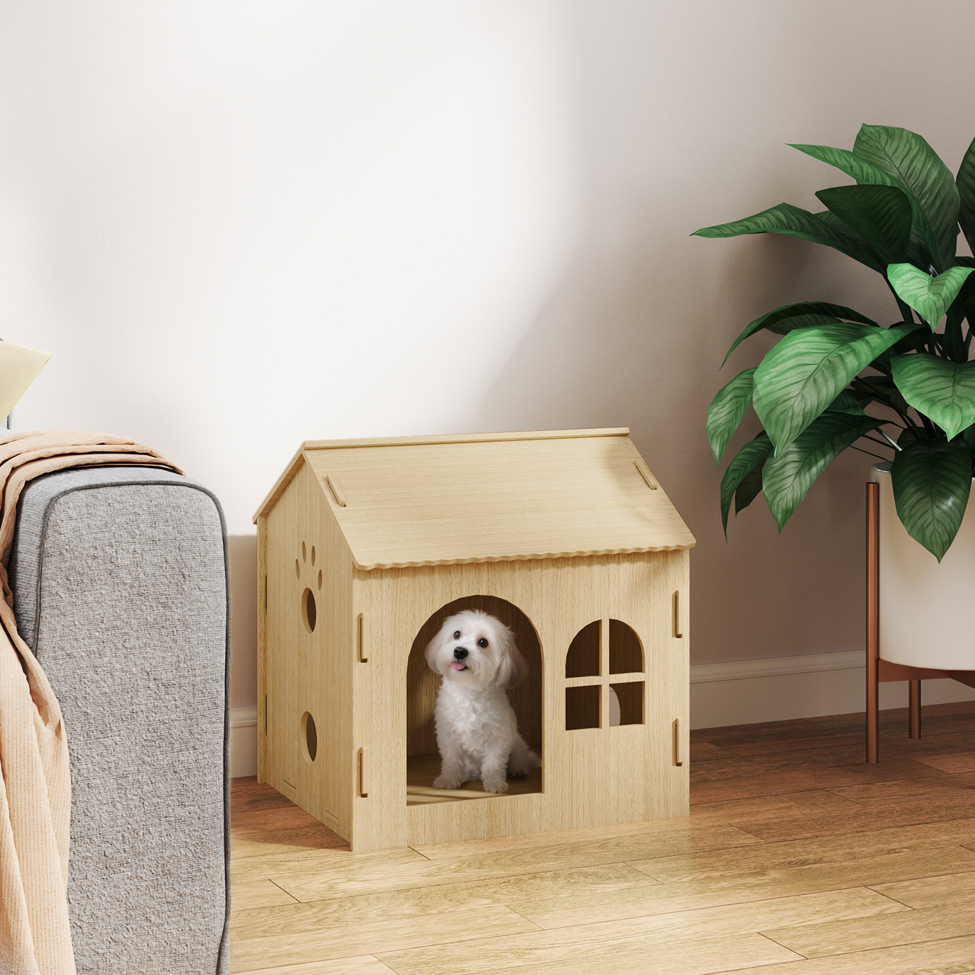Perro blanco pequeño sentado en cama para perro de madera con forma de casa, junto a sofá.