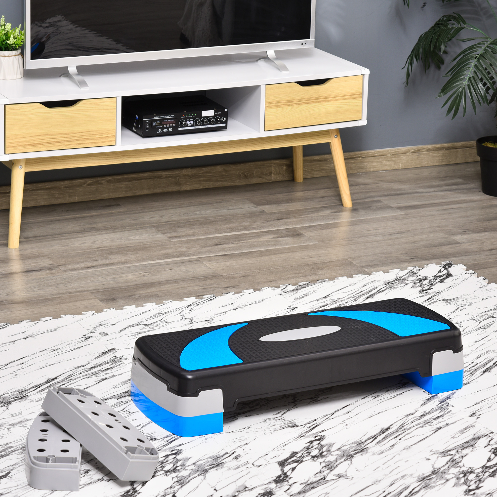 Un stepper aeróbico negro con acentos azules está sobre una alfombra de mármol.