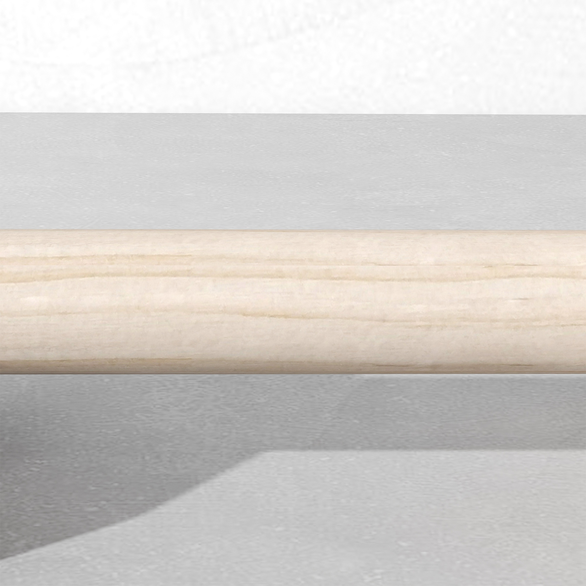 Un cilindro de madera clara yace sobre una superficie gris.