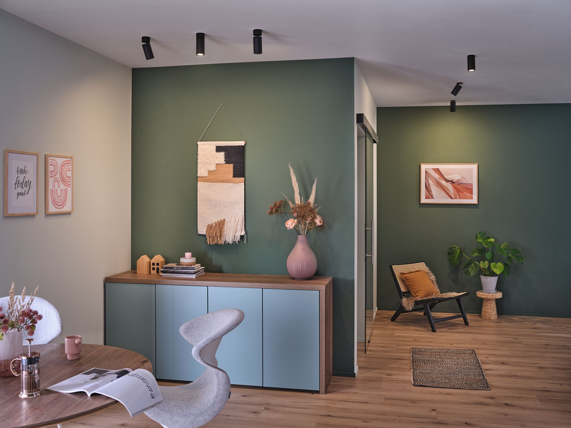 Ein Wohnzimmer mit grünen Wänden, Sitzmöbeln, einem Beistelltisch und einem Teppich.