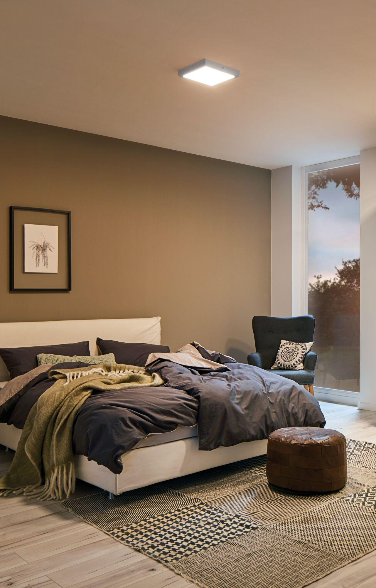 Ein Schlafzimmer mit einem Bett, Sessel, Teppich und Fenster.