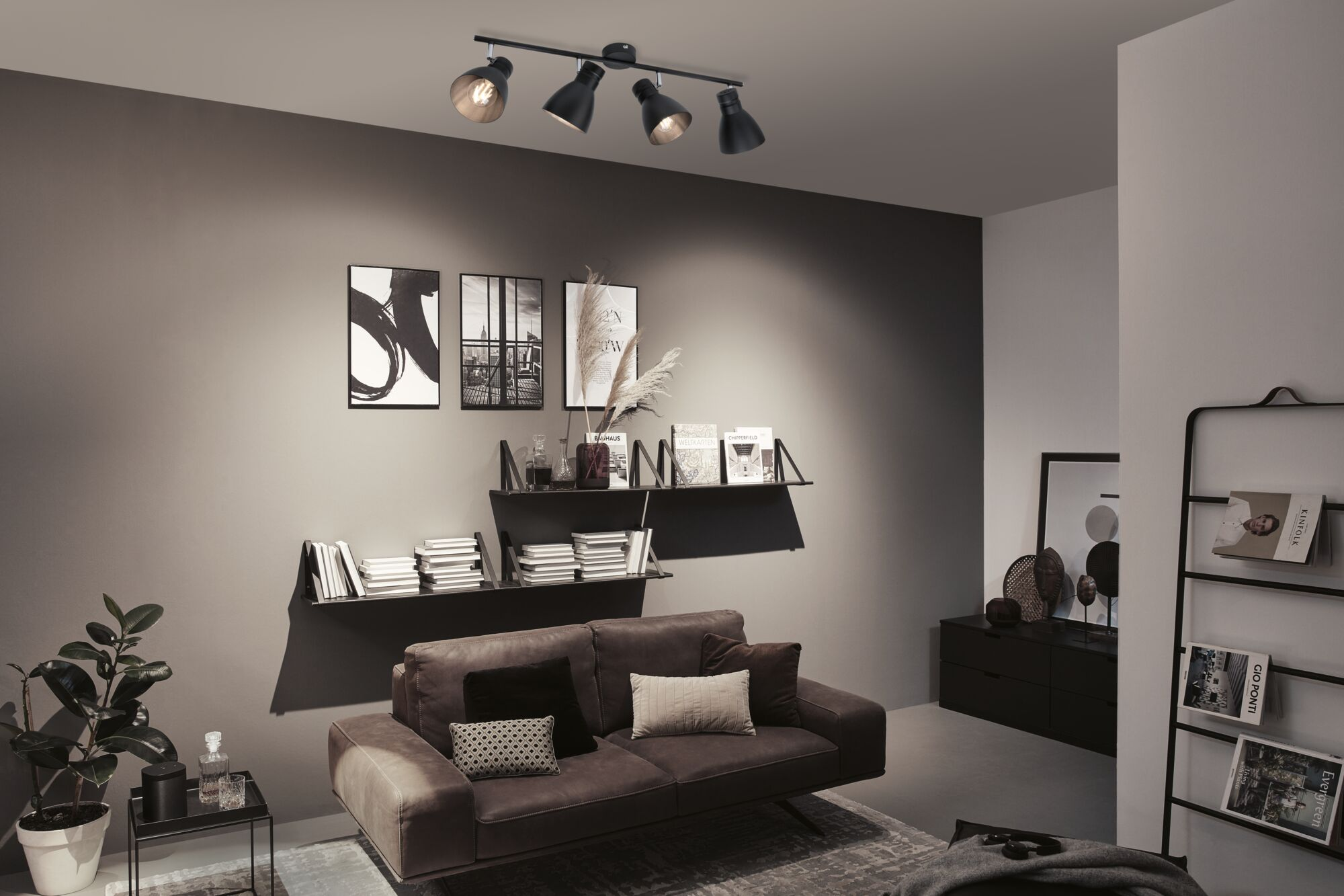 Brązowa skórzana sofa w nowoczesnym salonie z obrazami i półkami.