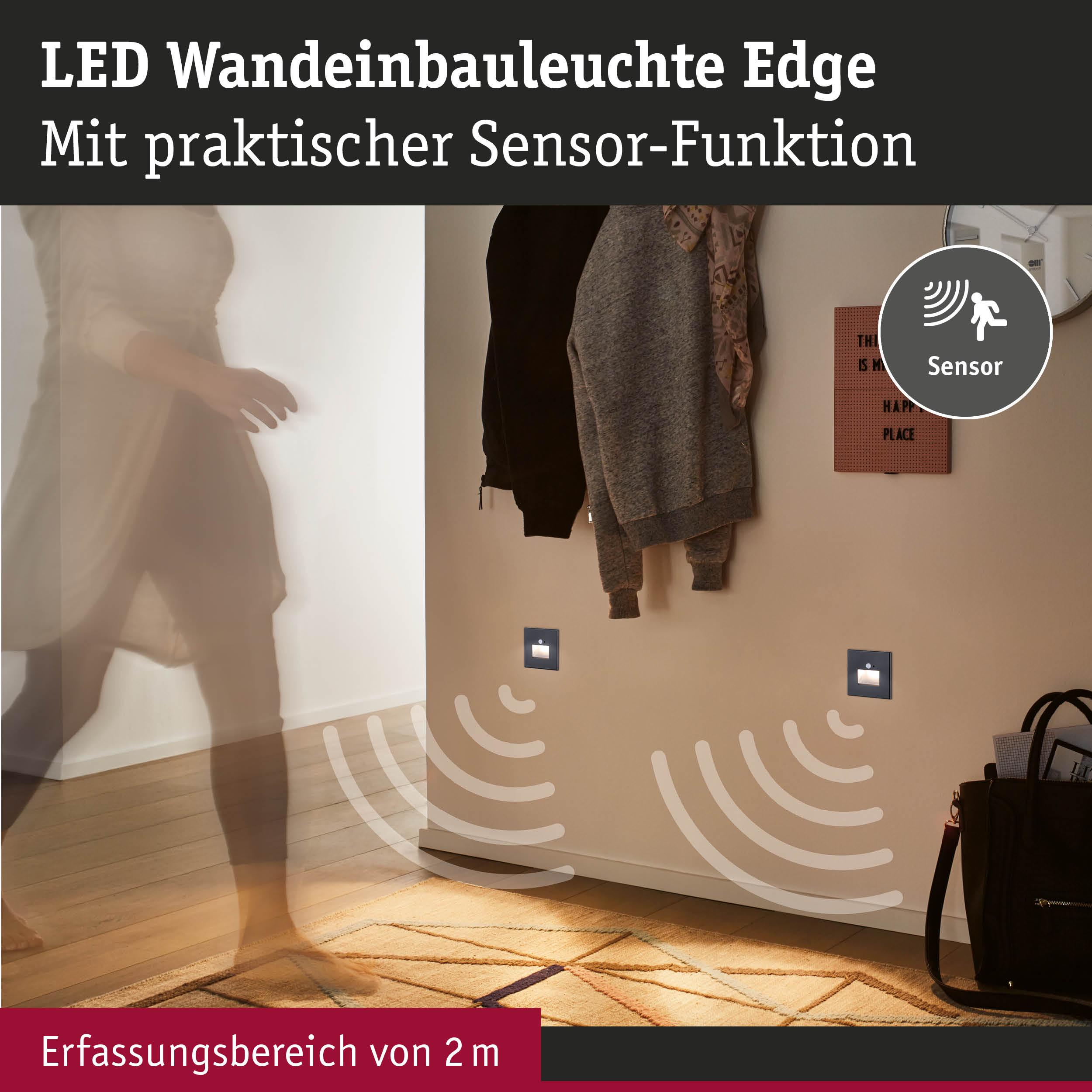 Person im Flur, Wandleuchten mit Sensorfunktion, Teppich und Tasche.
