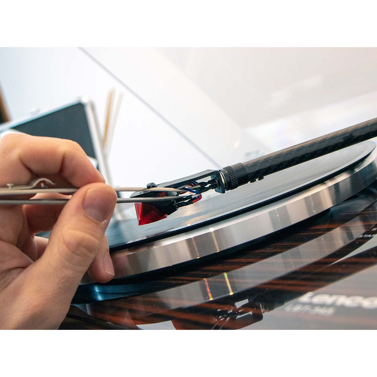 Osoba czyści igłę gramofonu pęsetą. Ujęcie z bliska.