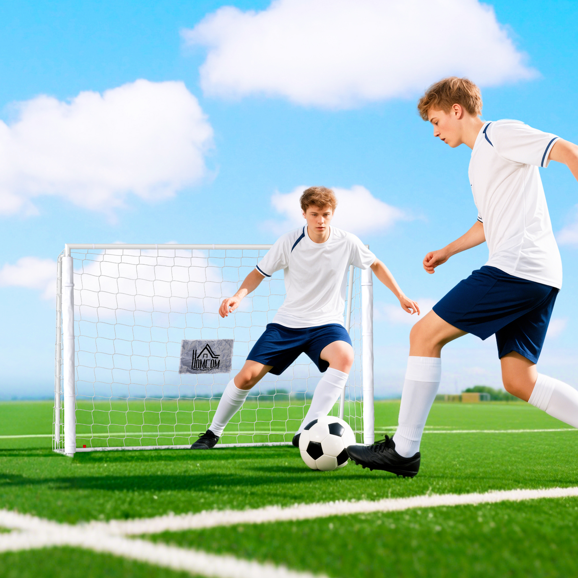 Dos chicos juegan al fútbol en un campo de césped artificial frente a una portería.