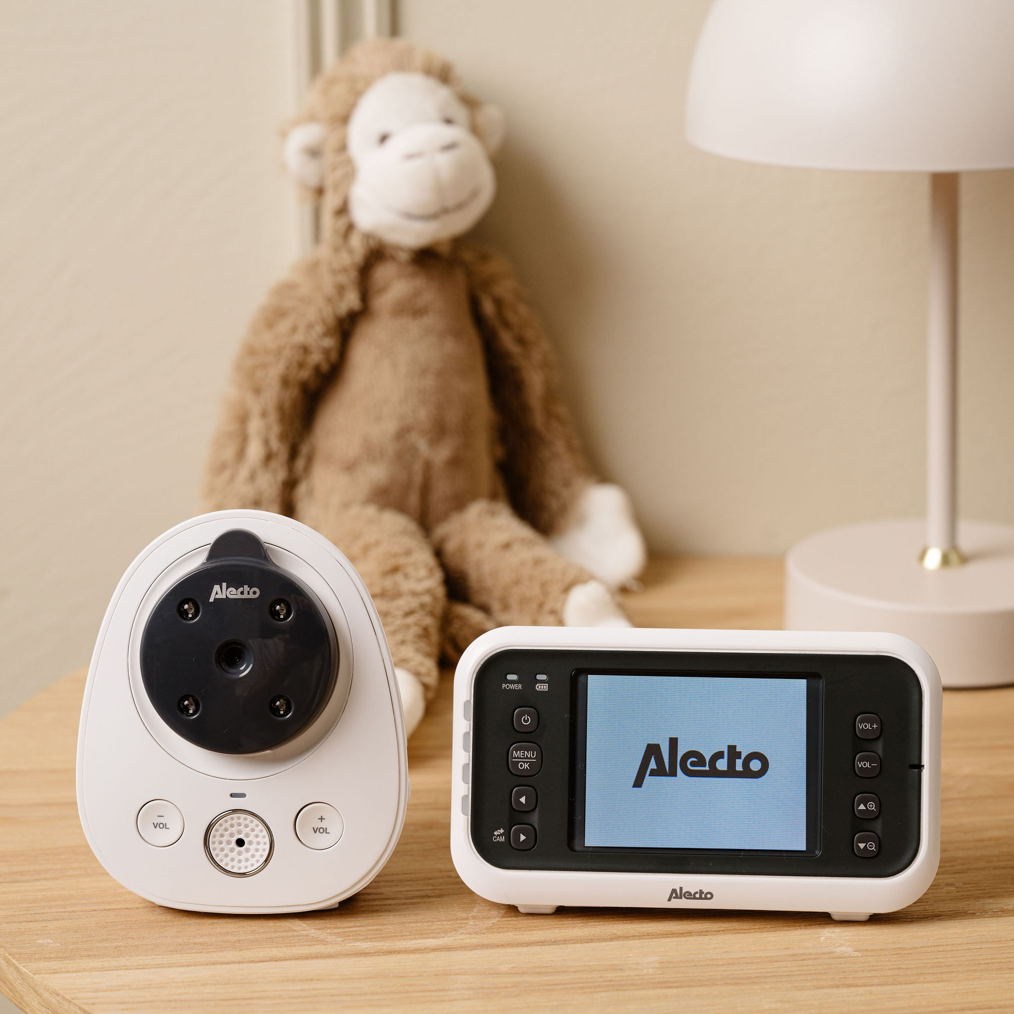 A baby monitor with camera and screen sit on a wooden table.