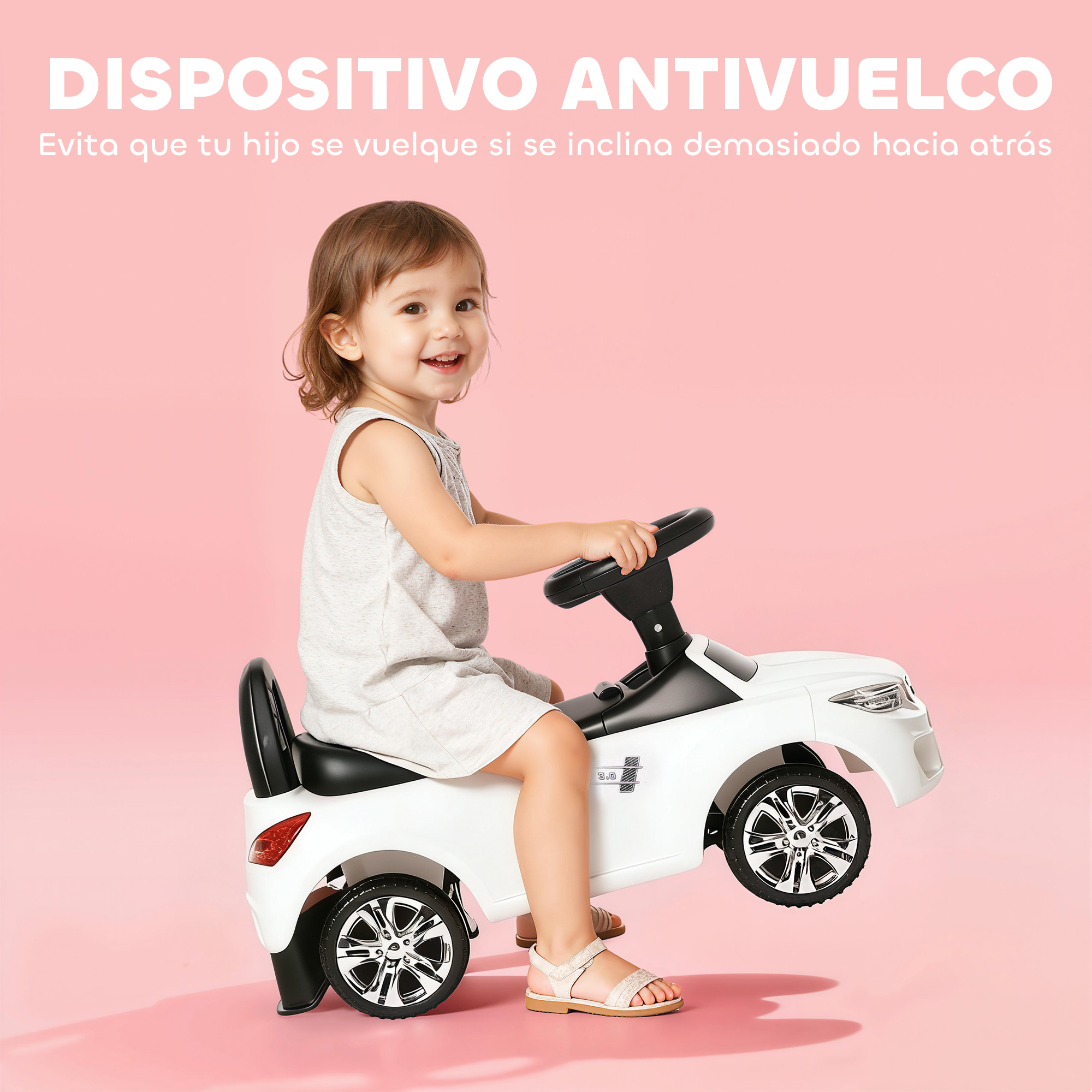 Un niño pequeño sonriente se sienta en un coche de juguete blanco sobre fondo rosa.