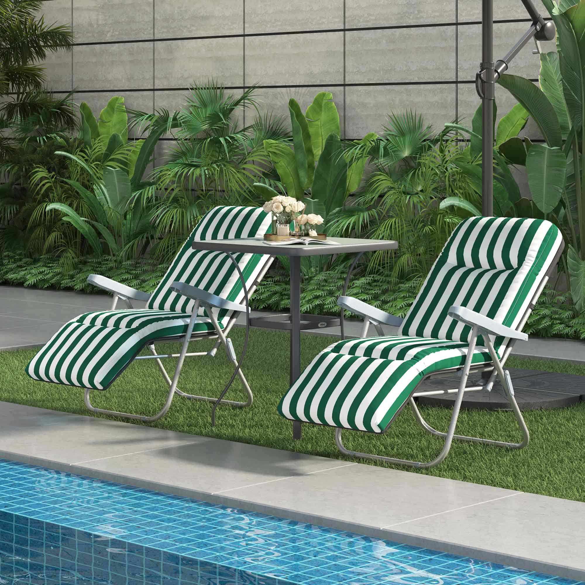 Dos tumbonas a rayas verdes y blancas junto a una mesa junto a una piscina.
