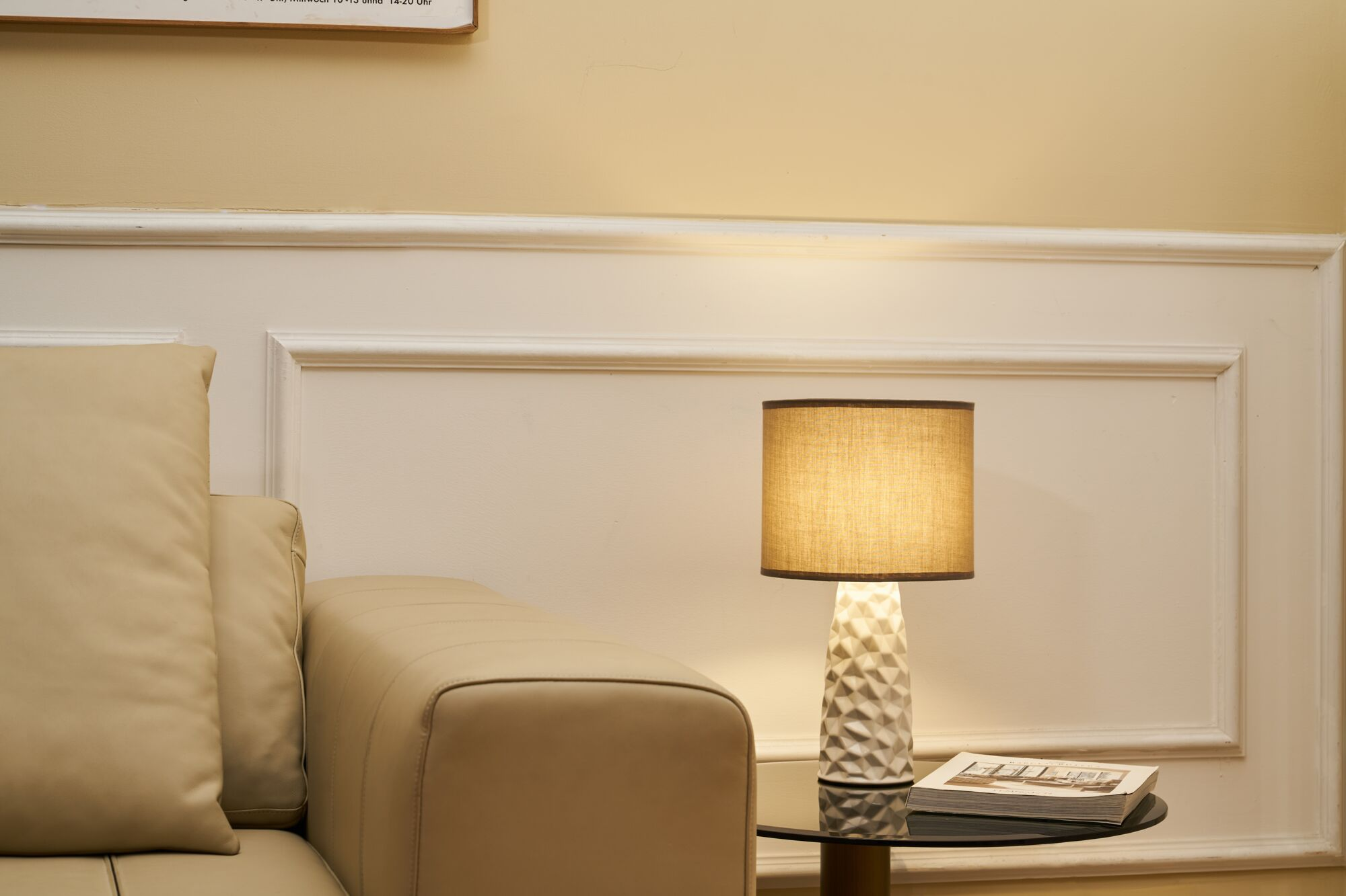 Beżowa sofa obok stolika z lampą i książką.