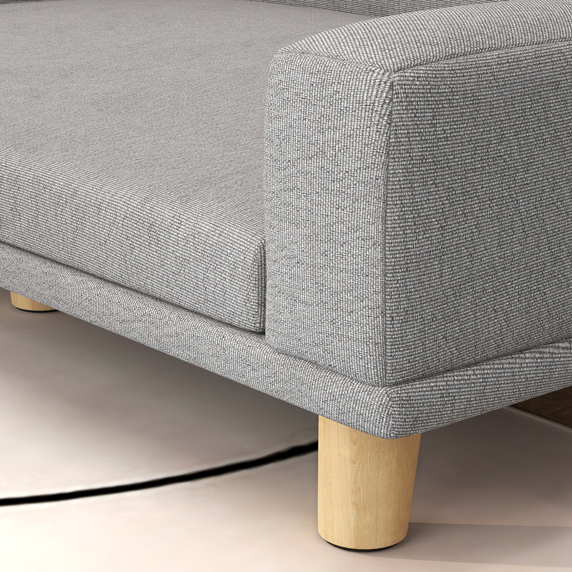 Primer plano de un sofá de tela gris con patas de madera sobre alfombra clara.