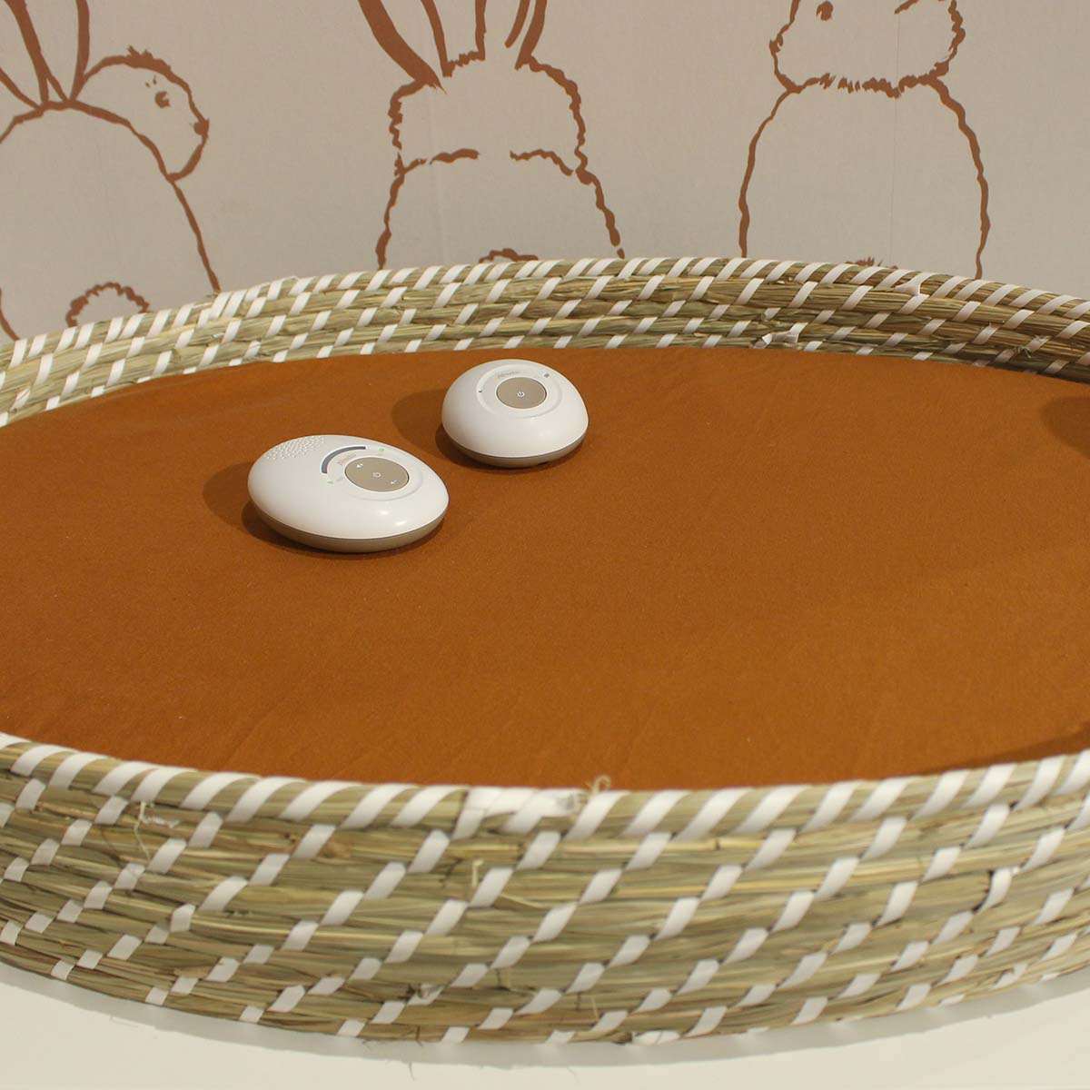 Two white round devices rest on brown fabric inside a woven basket.