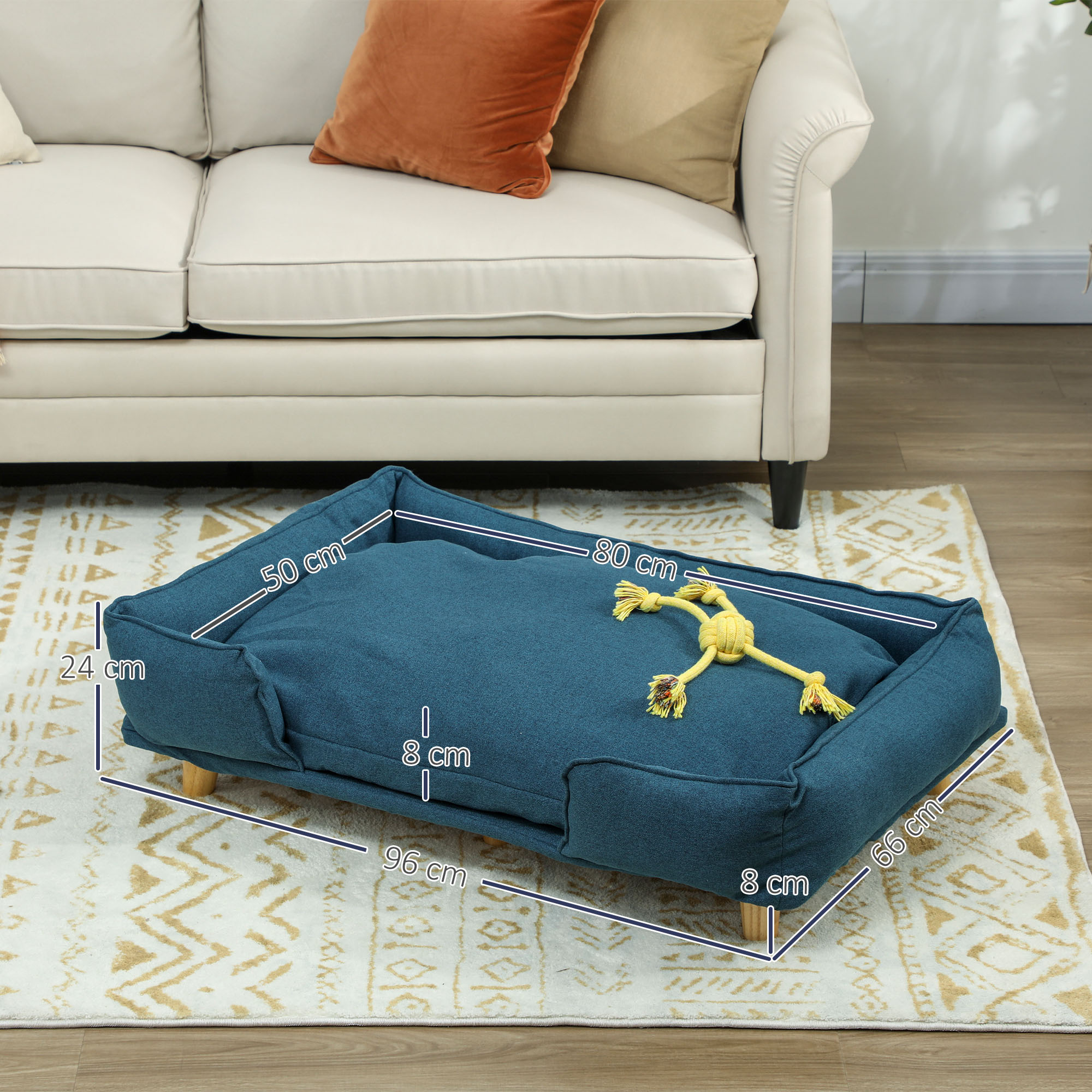 Una cama para perros azul con medidas y un juguete amarillo sobre una alfombra.