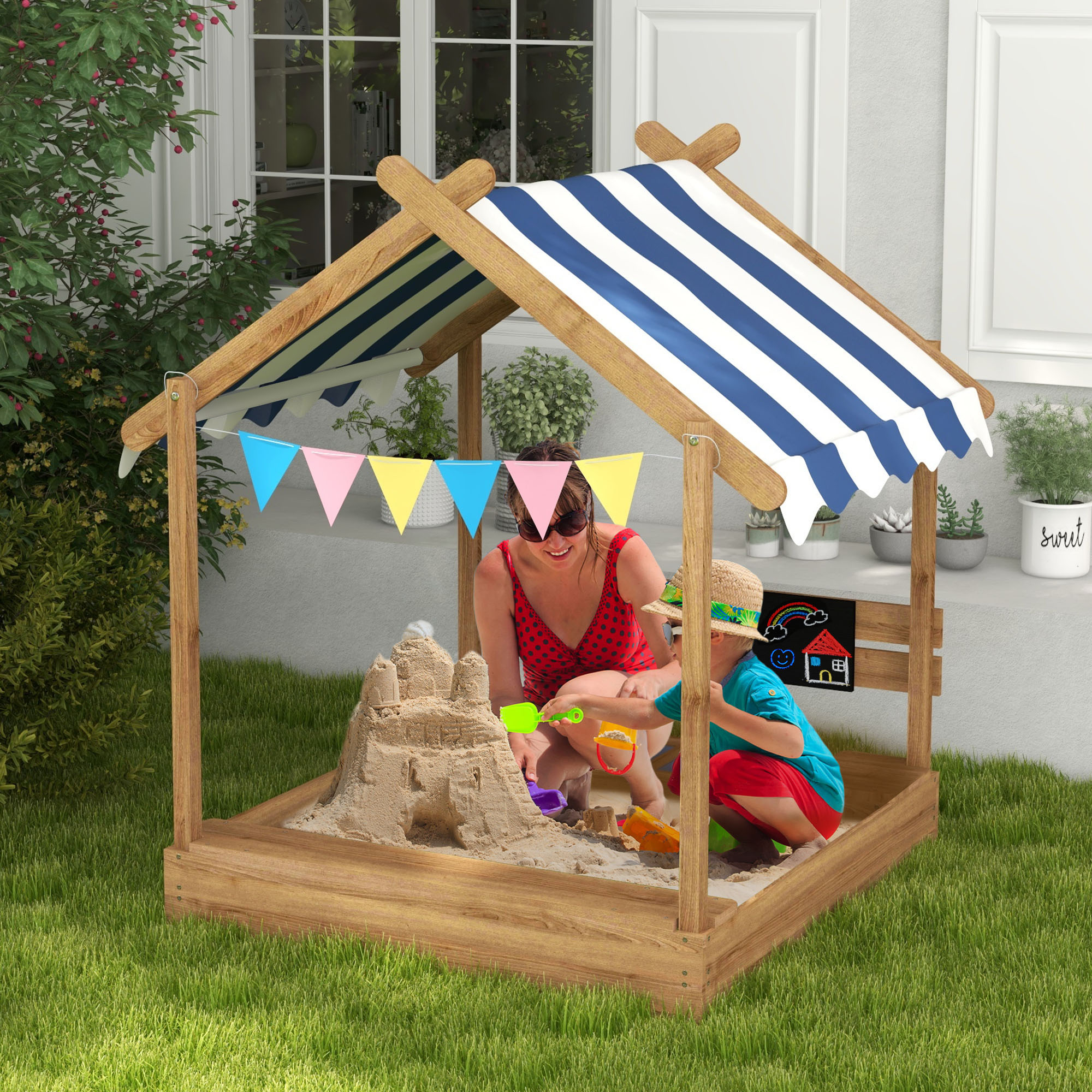 Mujer y niño construyen castillo de arena en casa de juegos con techo a rayas azules y banderines.
