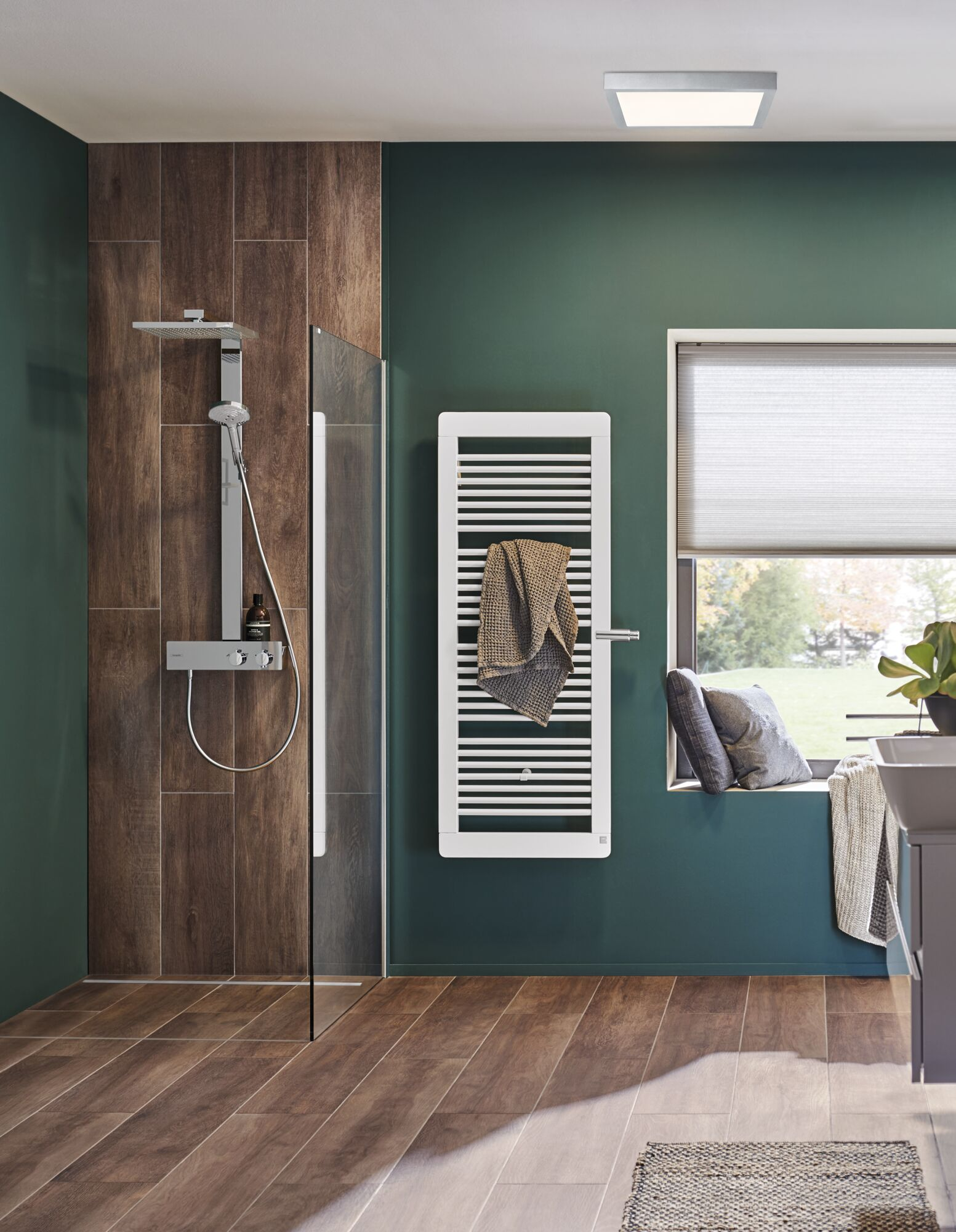 Bagno moderno con doccia, termosifone, finestra e lavandino. Pavimento effetto legno.