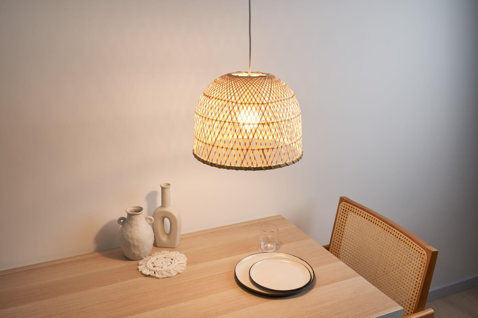 Stół jadalny z dwoma wazonami, serwetką, szklanką, talerzami i rattanowym krzesłem.