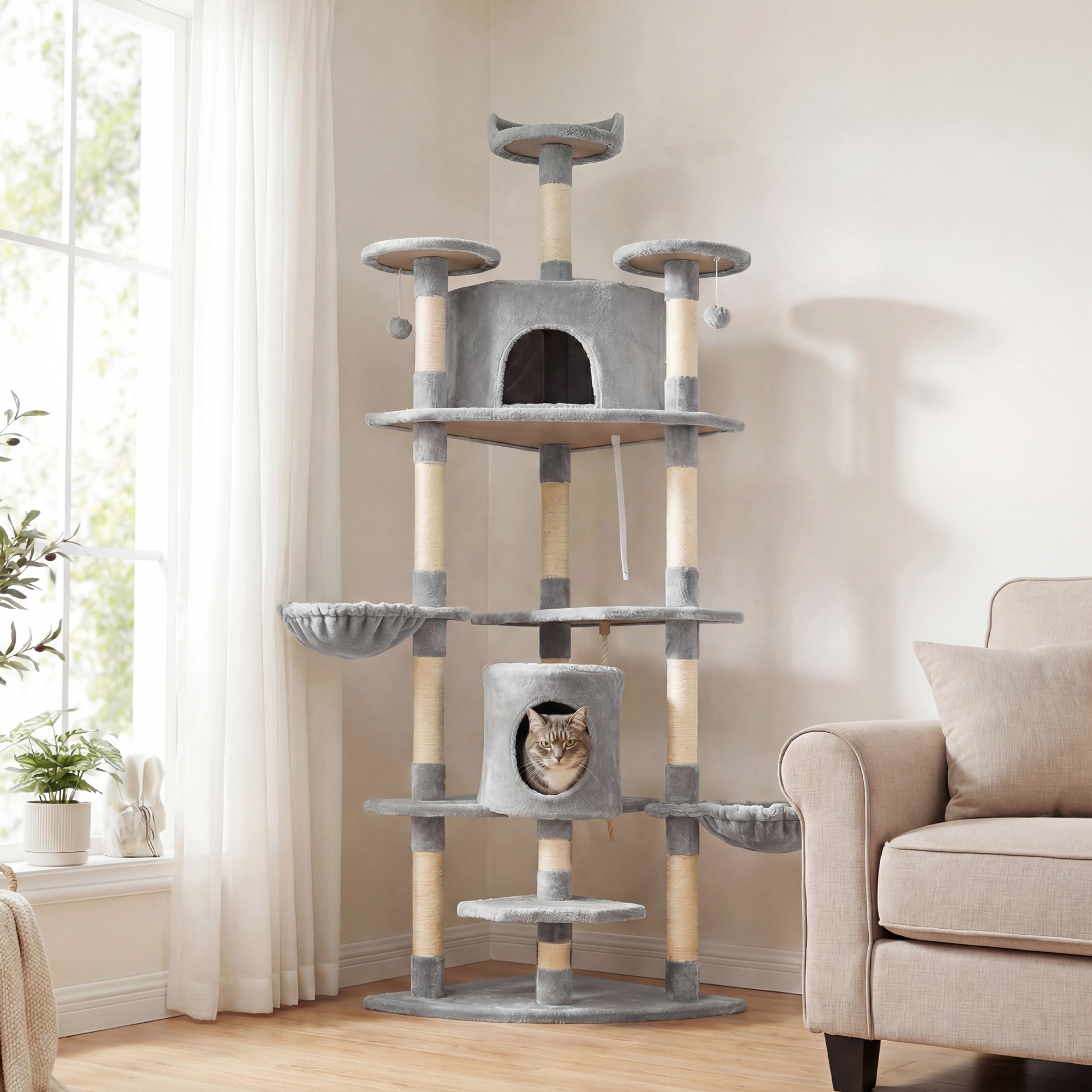 Un gato gris se sienta en un árbol para gatos de varios niveles junto a una ventana y un sofá.