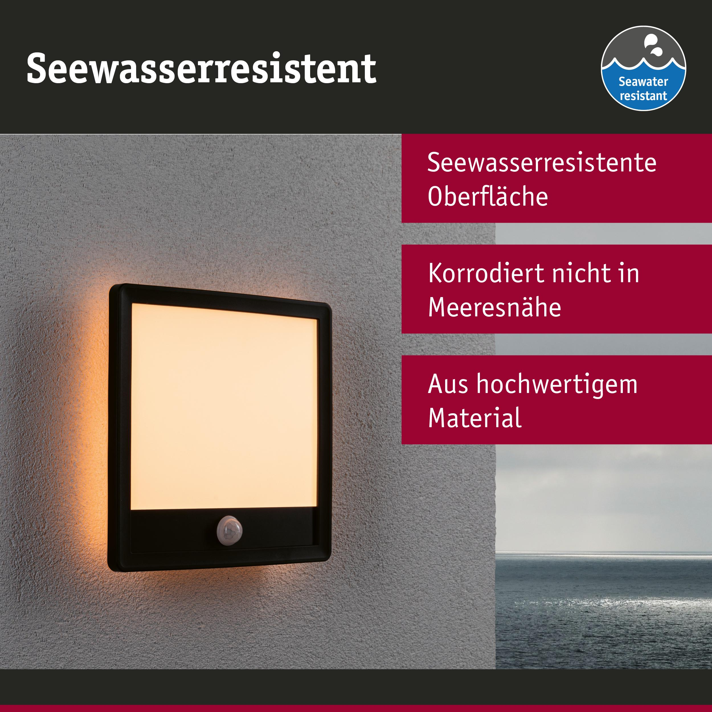 Eine seewasserbeständige Wandleuchte mit Bewegungsmelder leuchtet orange auf einer Wand neben dem Meer.
