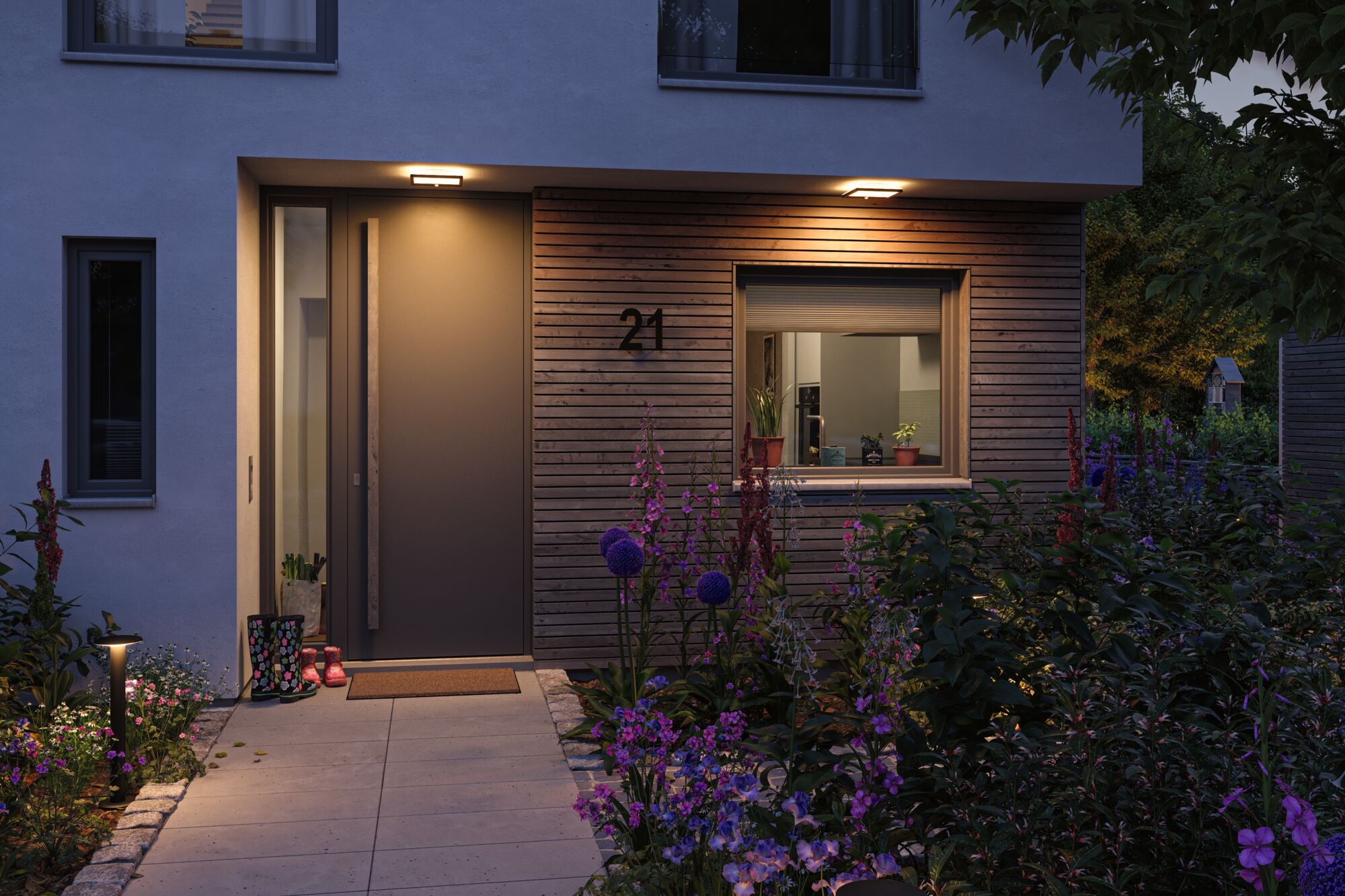 Moderne Haustür mit Holzverkleidung, beleuchtetem Weg und blühenden Blumen.