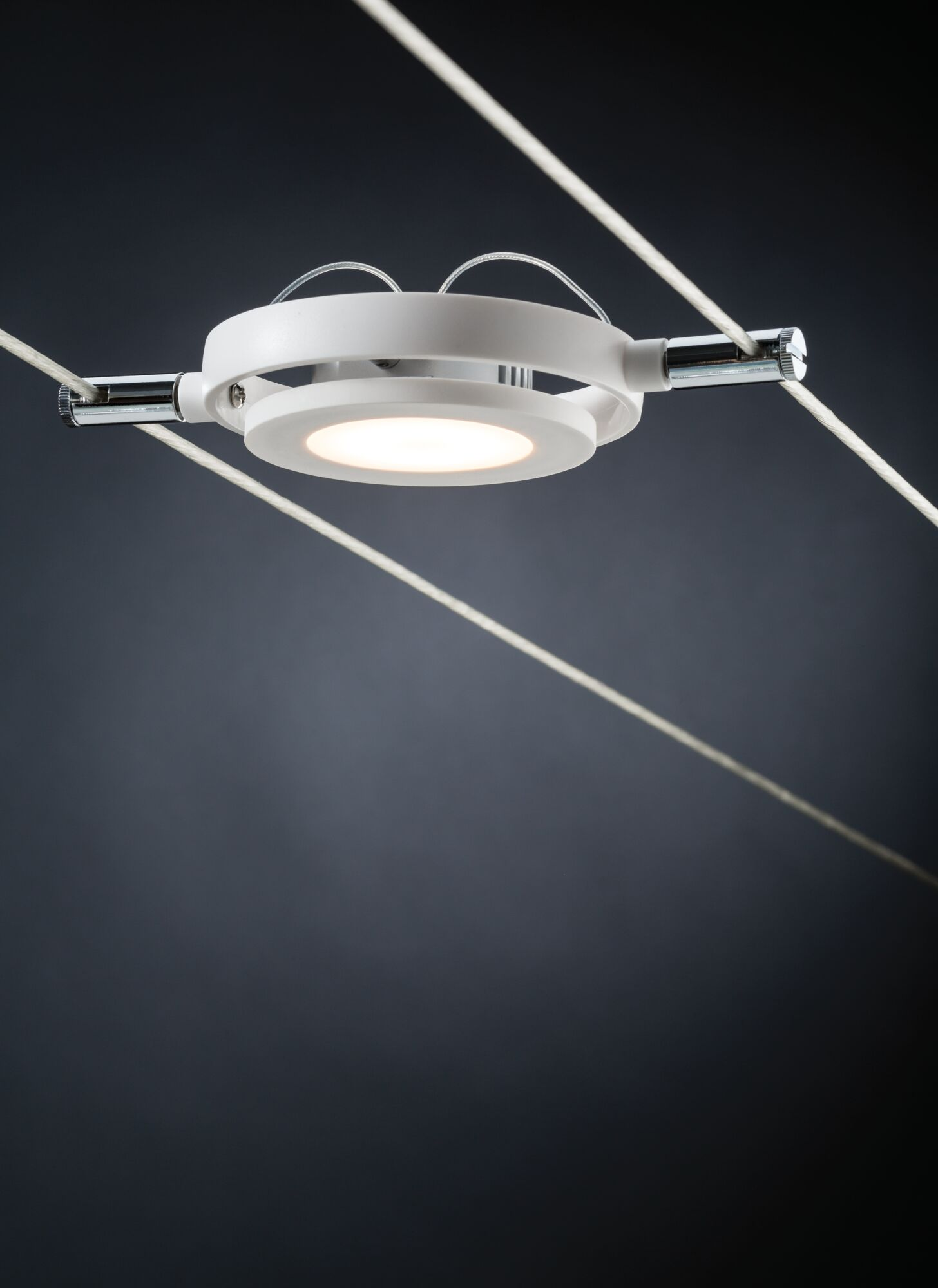 Una lampada da soffitto bianca con pannello circolare illuminato su sfondo scuro.
