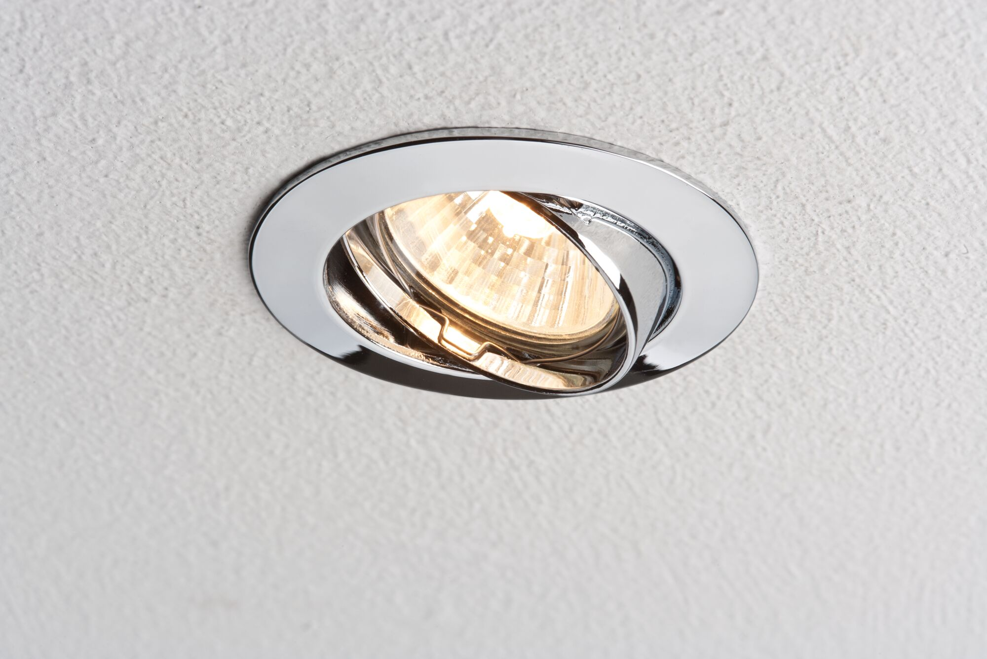 È visibile una lampada da soffitto incassata cromata con una lampadina calda e luminosa.