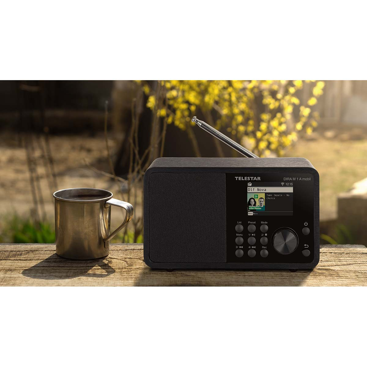 A black Telestar radio sits on a wooden table next to a metal mug.
