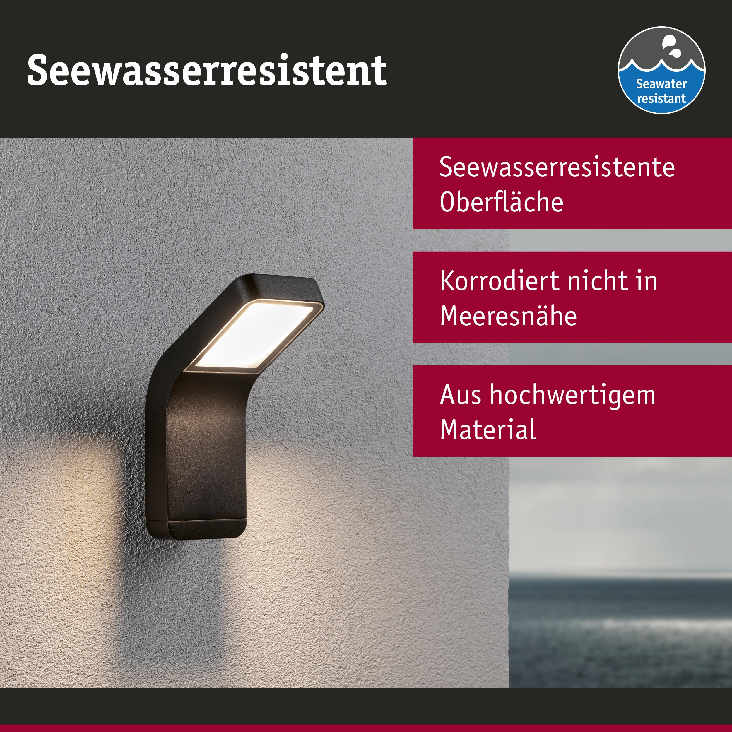 Schwarze Wandleuchte mitettivo LED Licht an einer grauen Wand, Meer im Hintergrund.