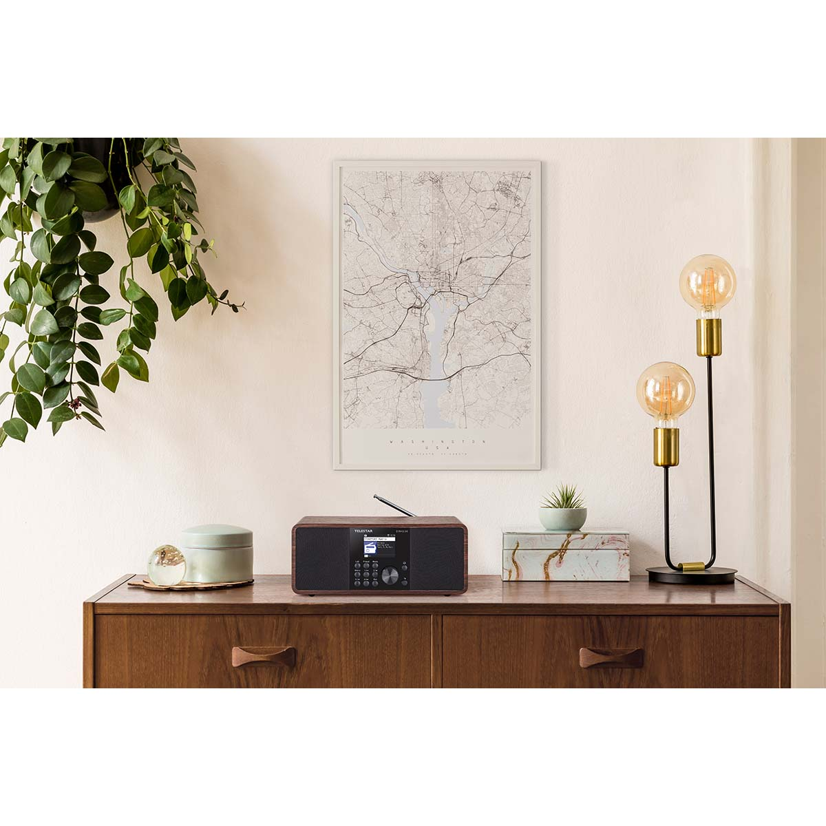 A wooden radio sits on a dresser next to a lamp and a map.