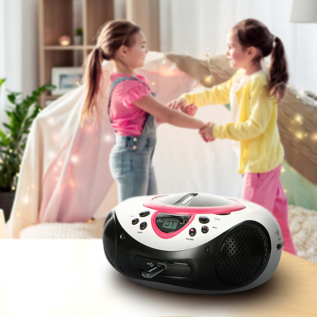 Deux filles dansent dans une pièce confortable, un lecteur CD au premier plan.