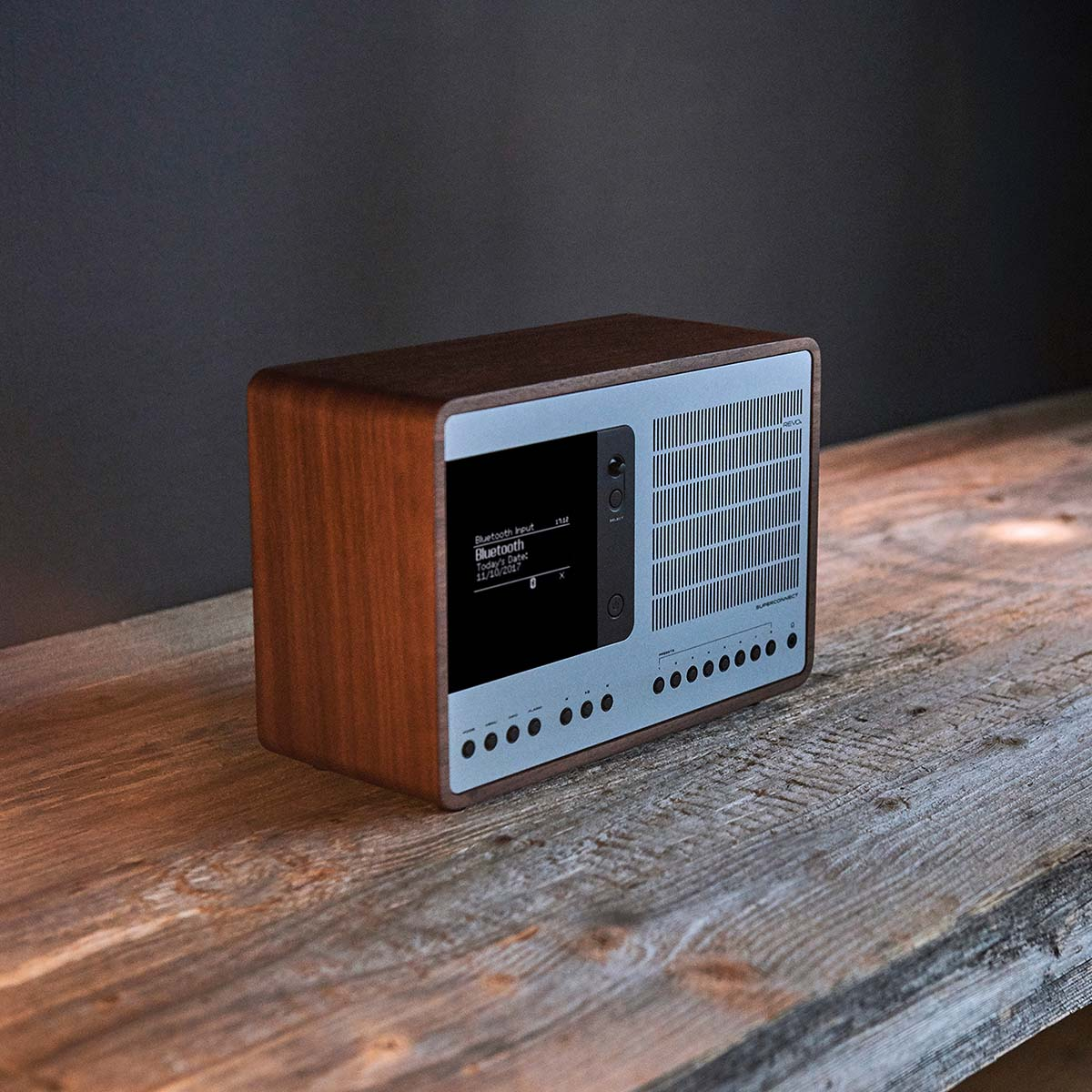 Ein Holzradio mit silberner Vorderseite und Bildschirm steht auf einem Holztisch.