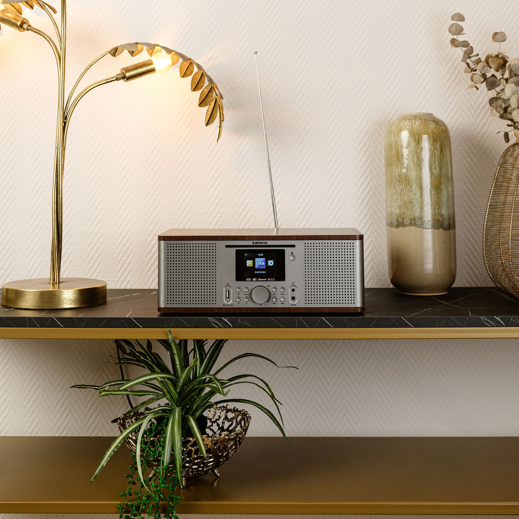 Una radio DAB con cornice in legno su uno scaffale con vasi e una lampada.