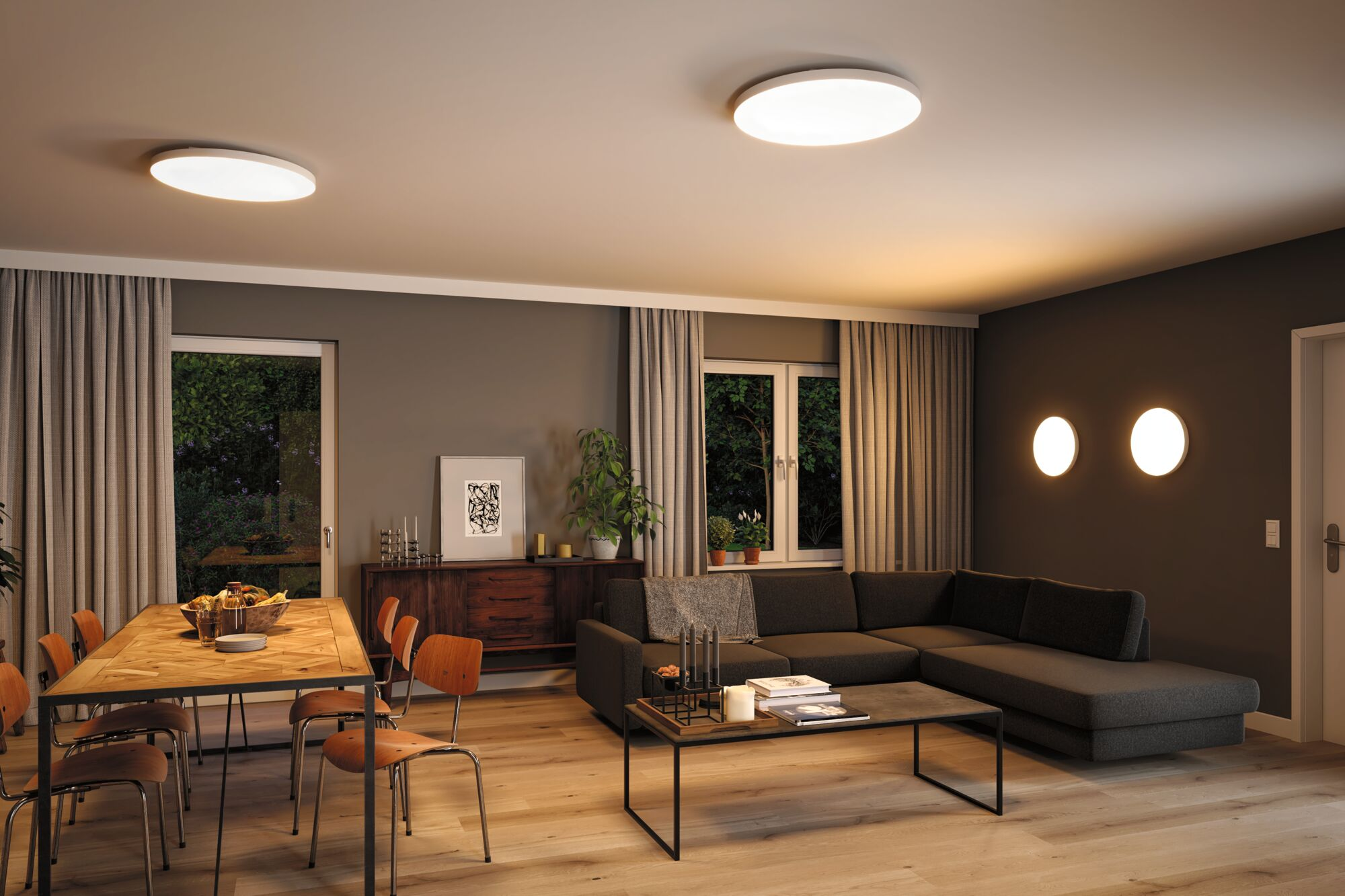 Ein Wohnzimmer mit Essbereich, dunklem Sofa, Holztisch und Stühlen.