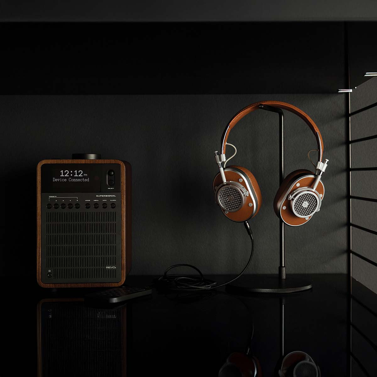 Une radio en bois avec écran et casque sur un support sur table noire.