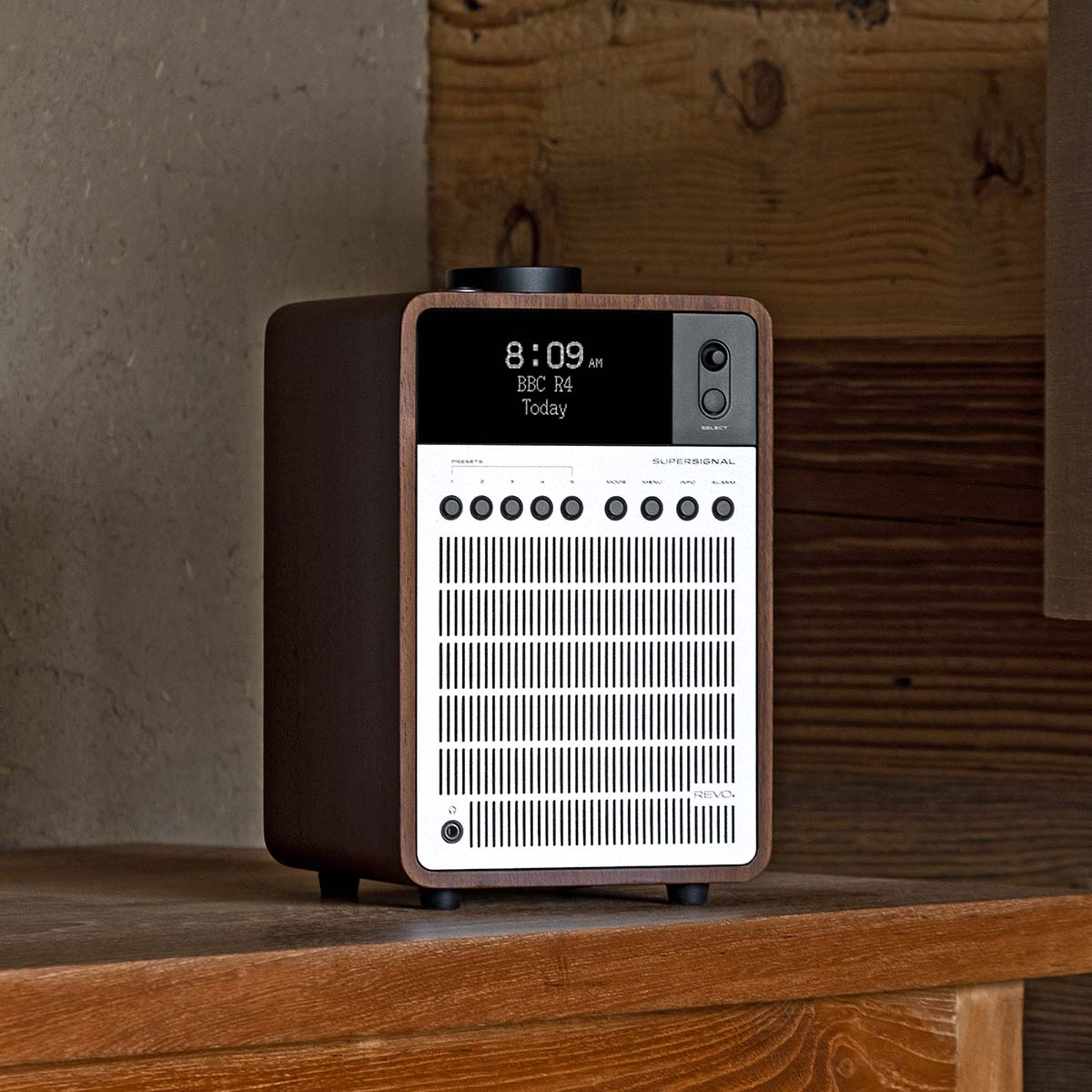 Een bruine houten radio met wit luidsprekerrooster en display.