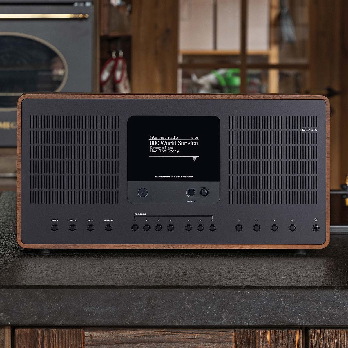A black Revo Superconnect Stereo internet radio with a wood frame sits on a dark countertop.