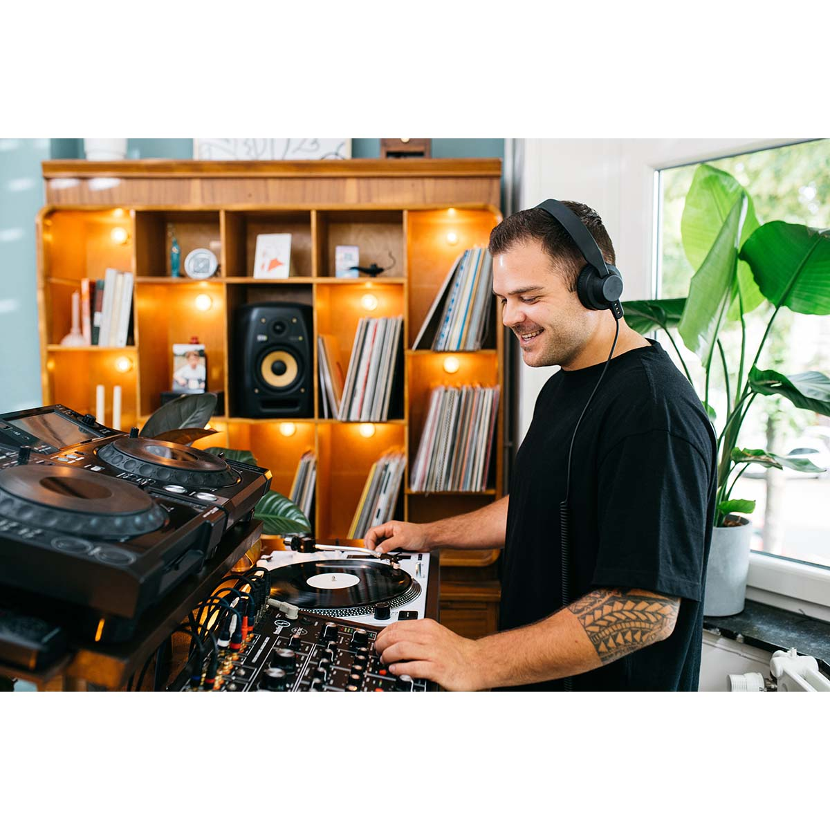 Un hombre con auriculares mezcla música en un tocadiscos.