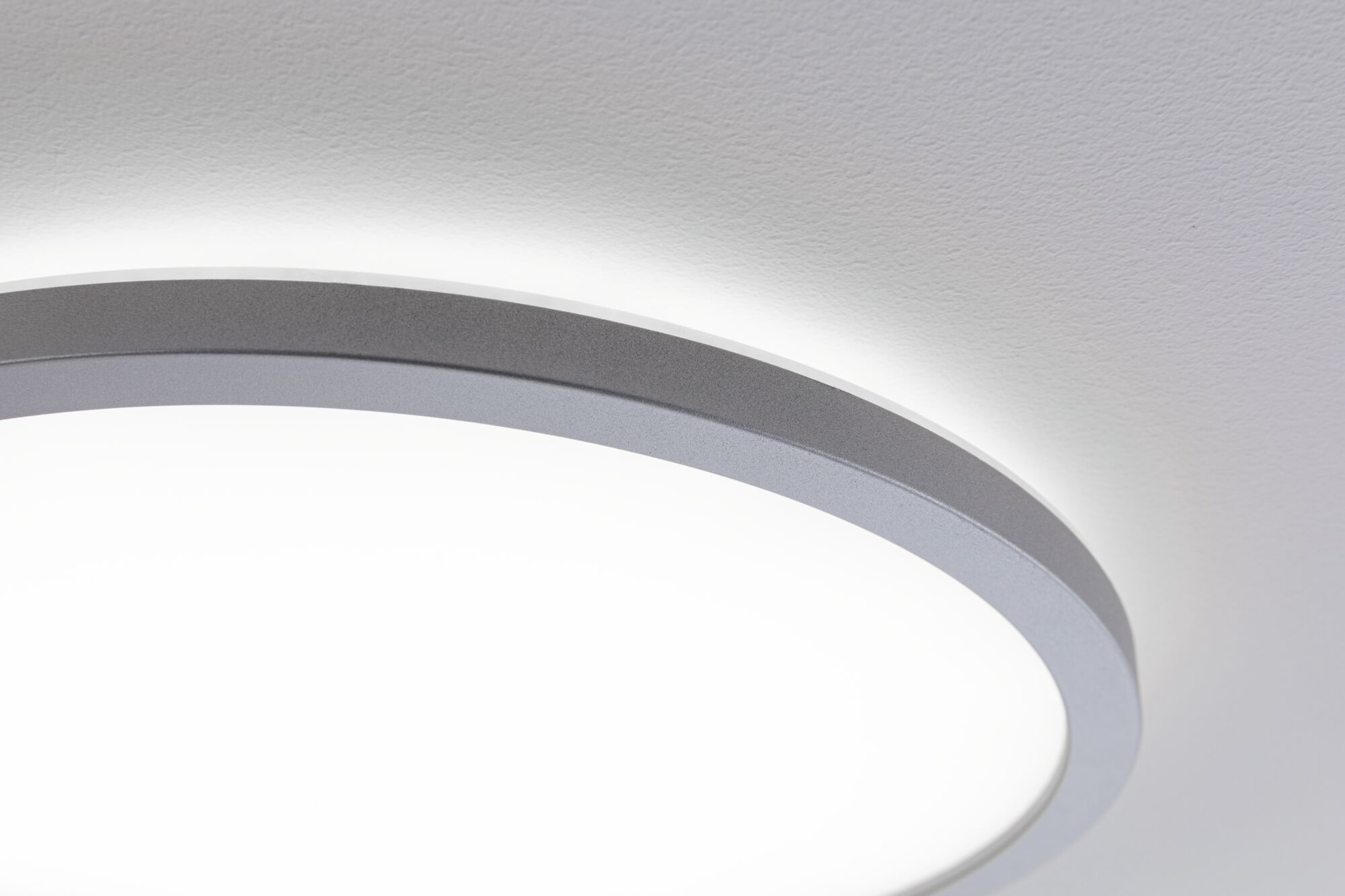 Una plafoniera luminosa con bordo argentato su soffitto bianco.