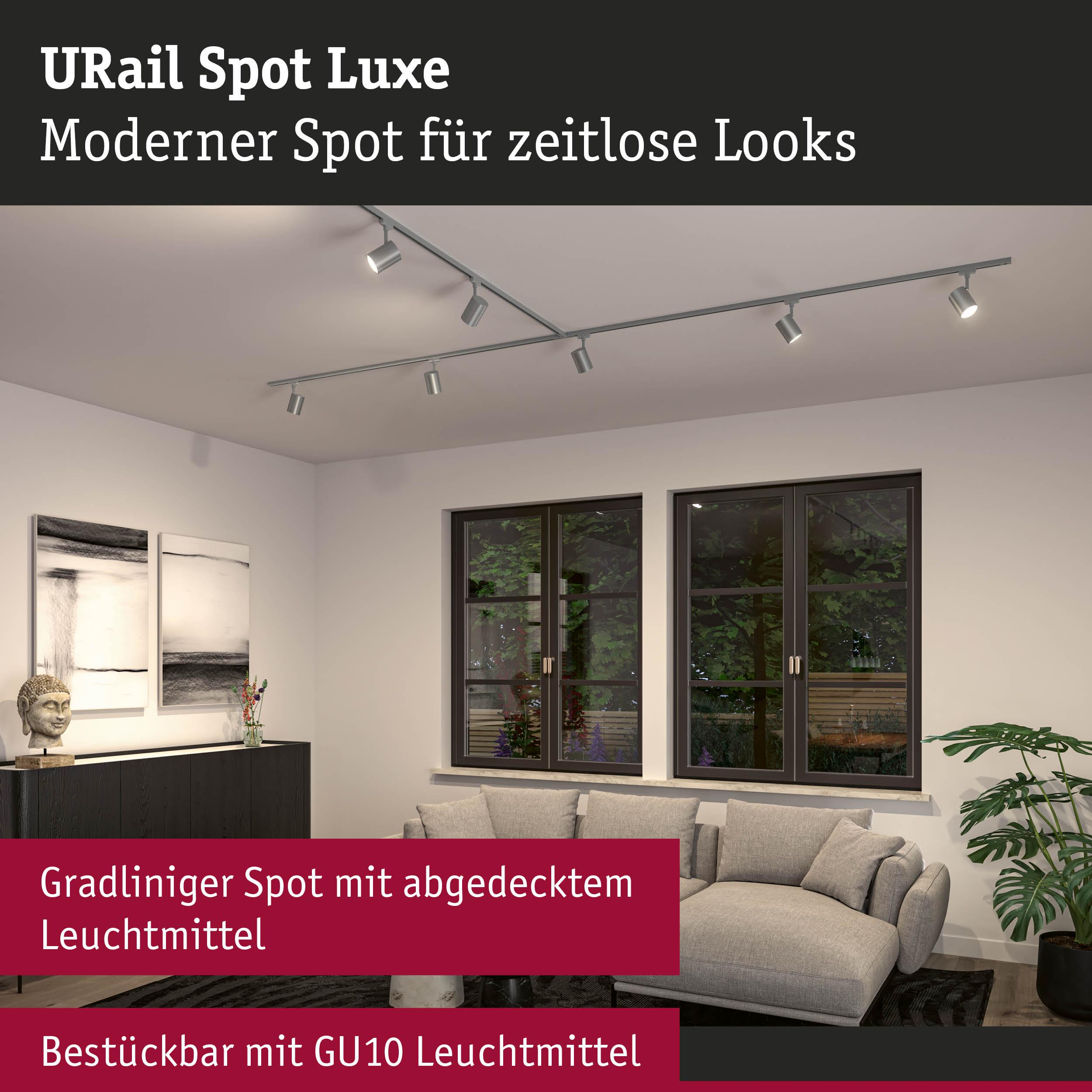 Ein moderner Schienenstrahler mit silbernen Spots über einem Sofa und Fenstern.