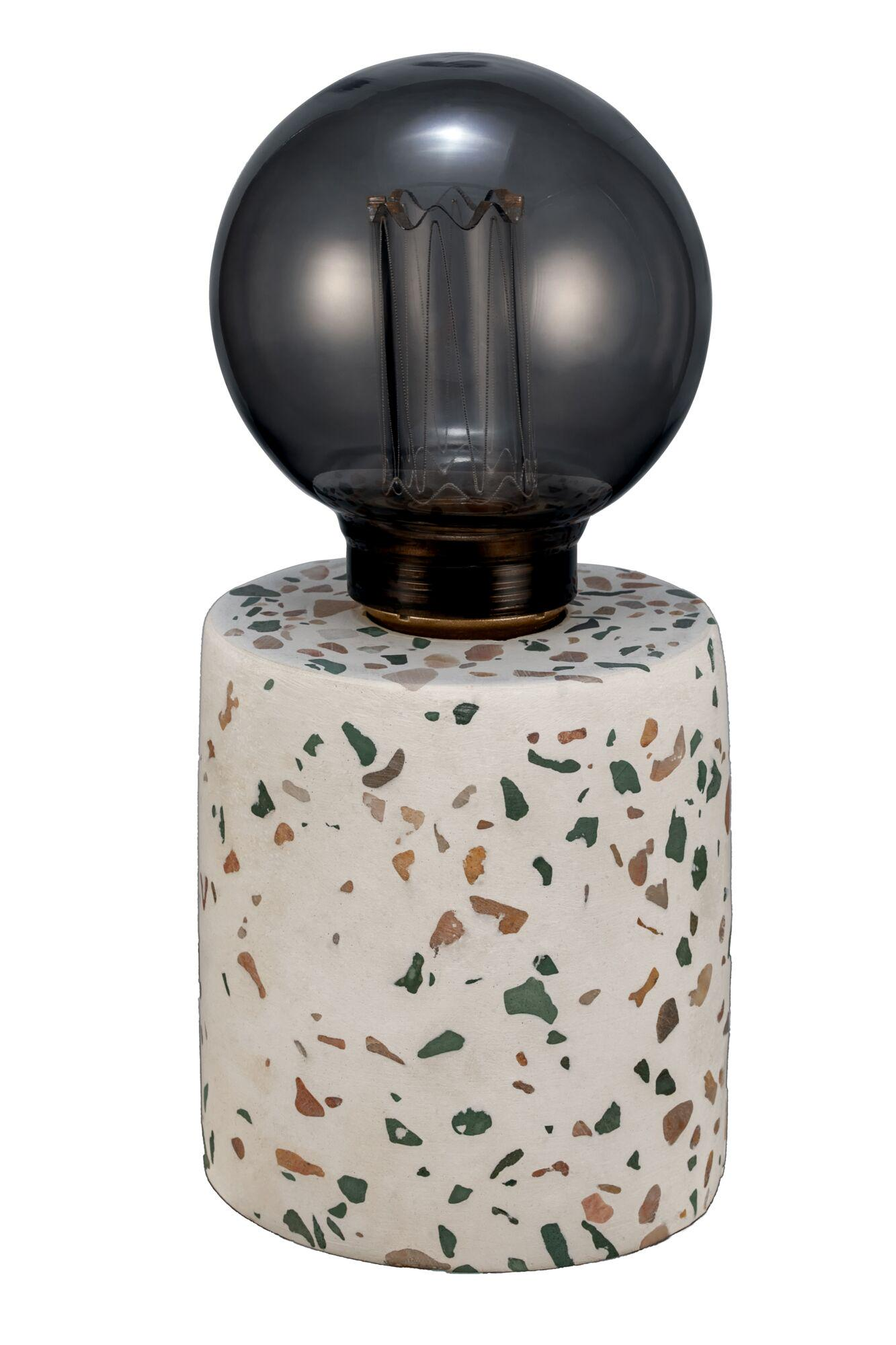 Biała lampa cylindryczna z wzorem terazzo i szaro-dymną żarówką.