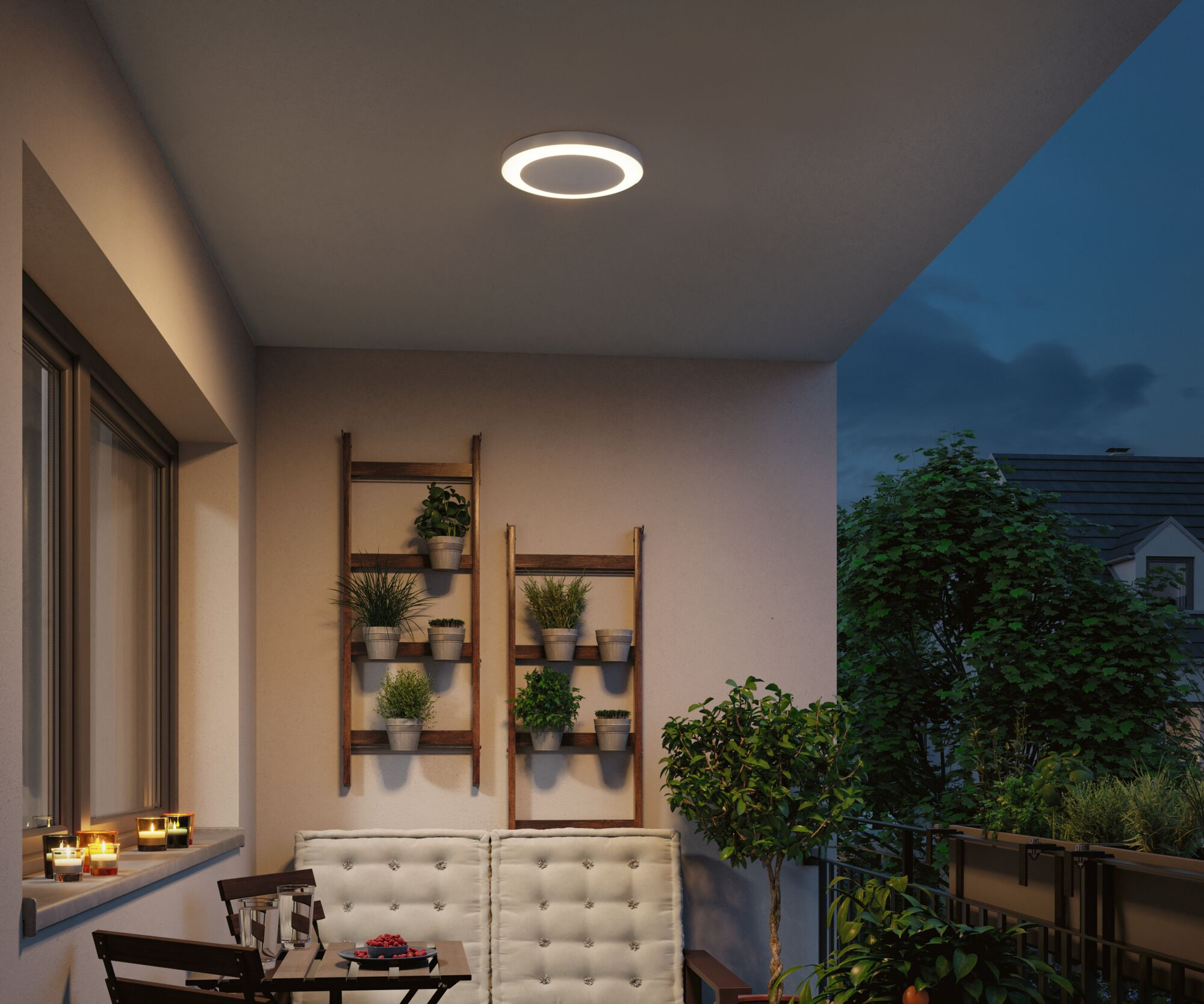 Balkon mit Sitzgelegenheiten, Pflanzenregalen und Kerzen bei Nacht.