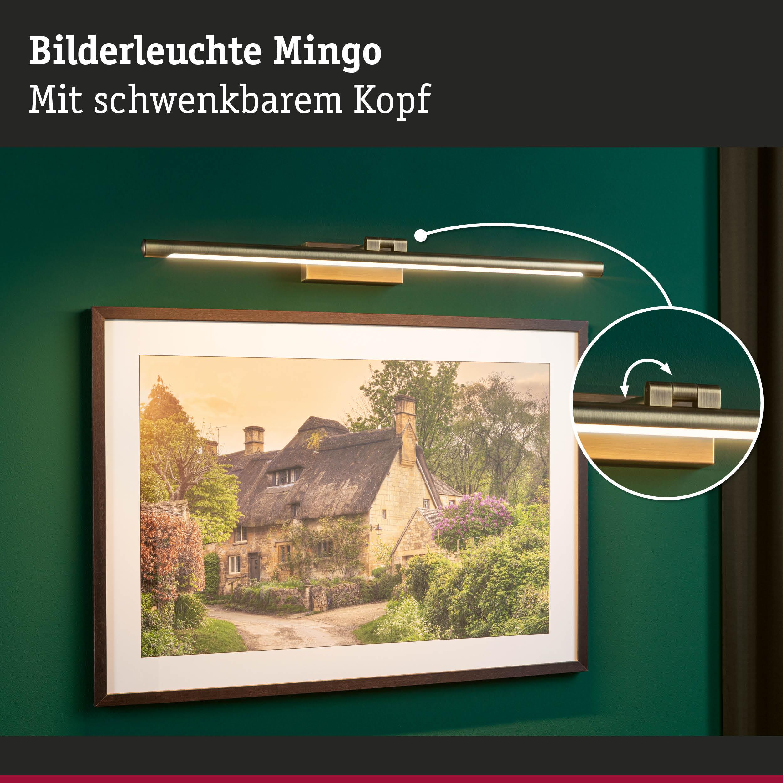 Lampa nad obrazem chałupy z krytym strzechą dachem.